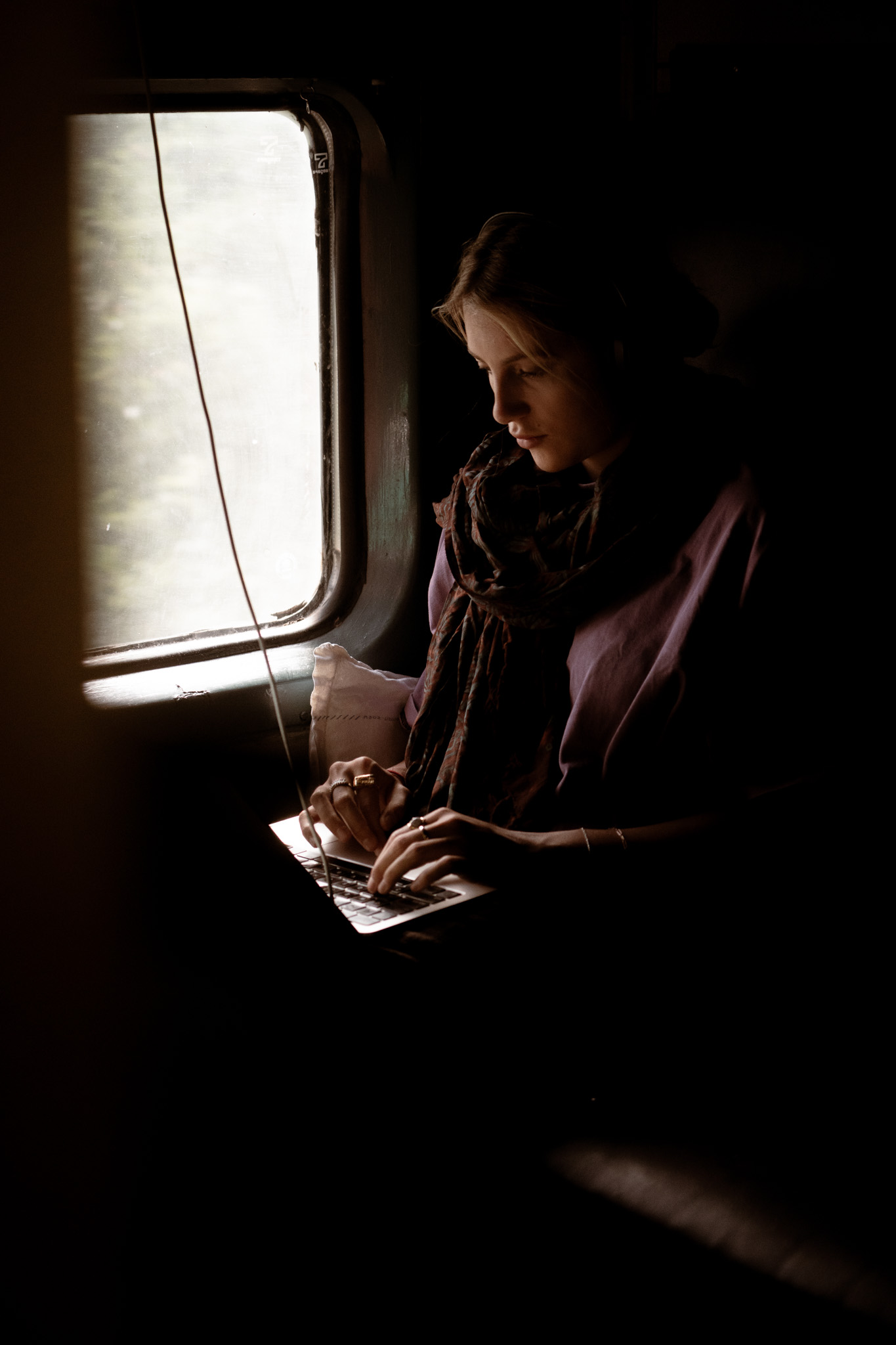 Anna writing on laptop by train window