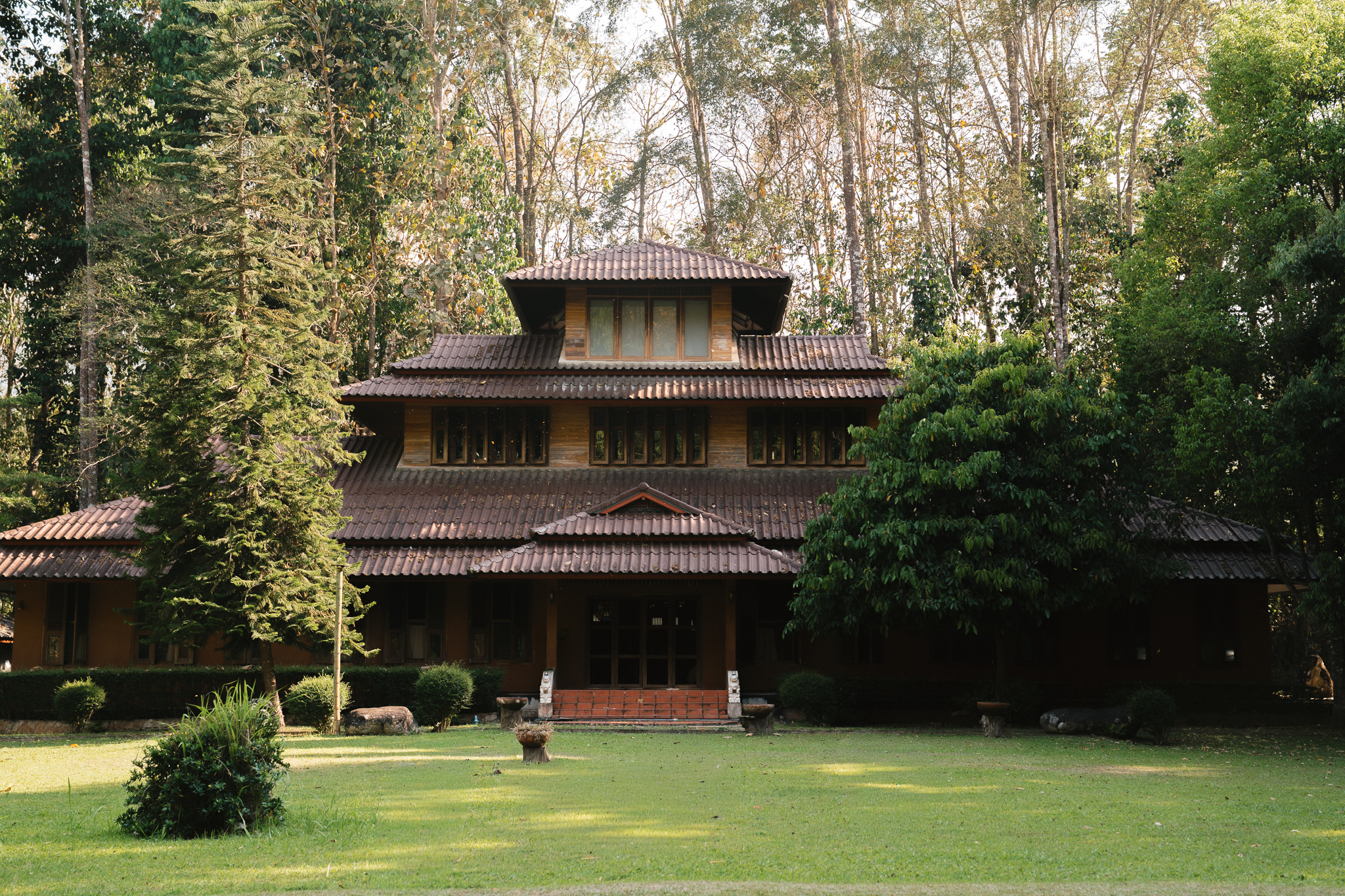 Traditional Thai wooden monastery building surrounded by tall trees