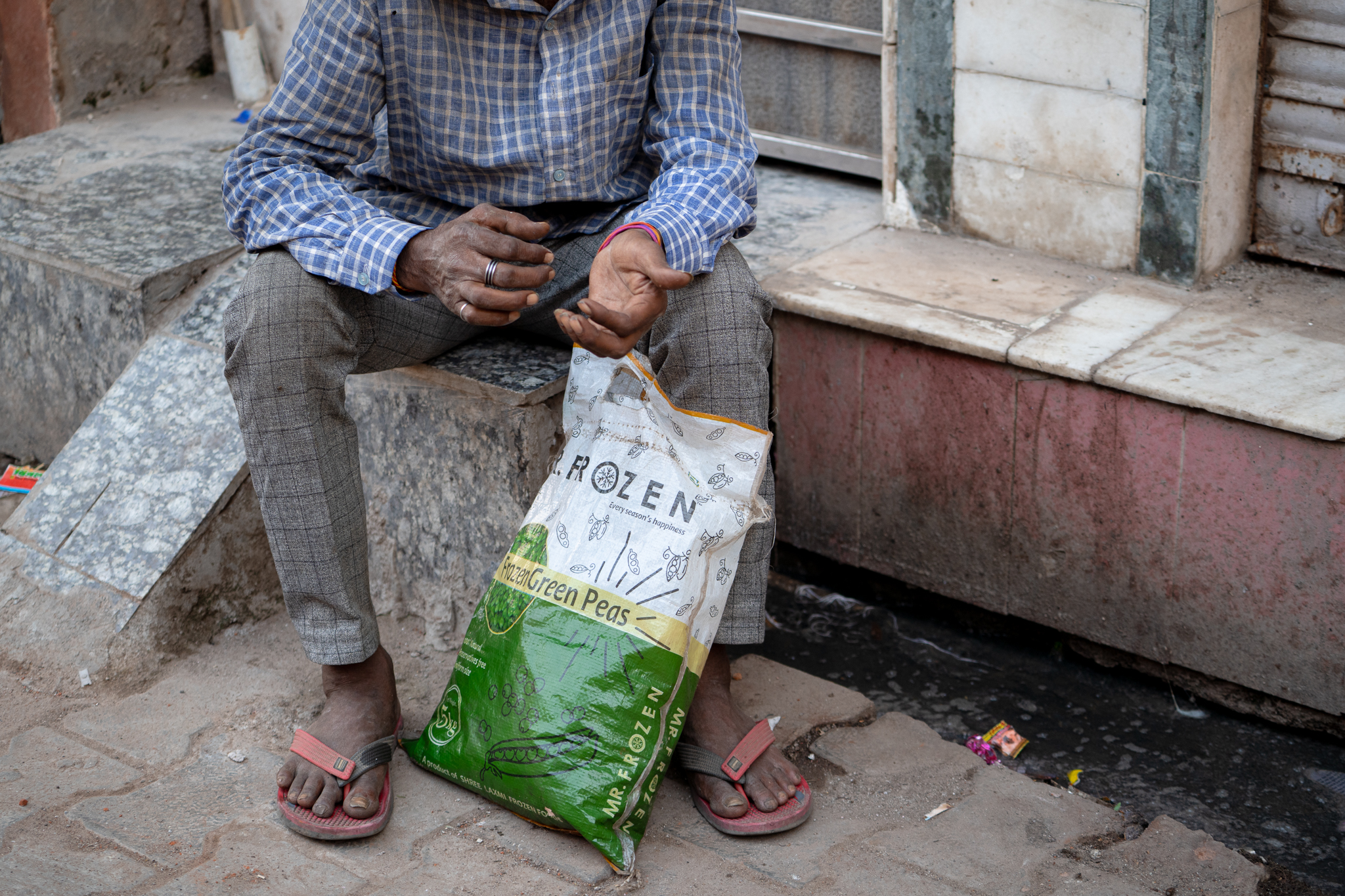Man sitting on steps with a bag of frozen green peas