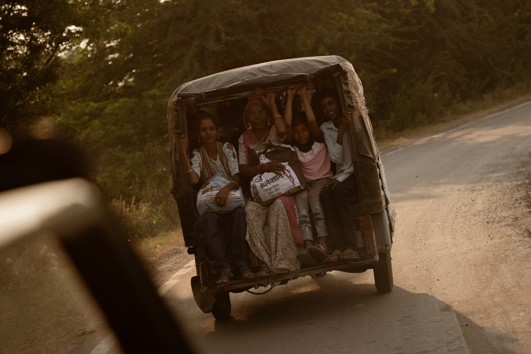 Family riding in auto-rickshaw on dusty road in India