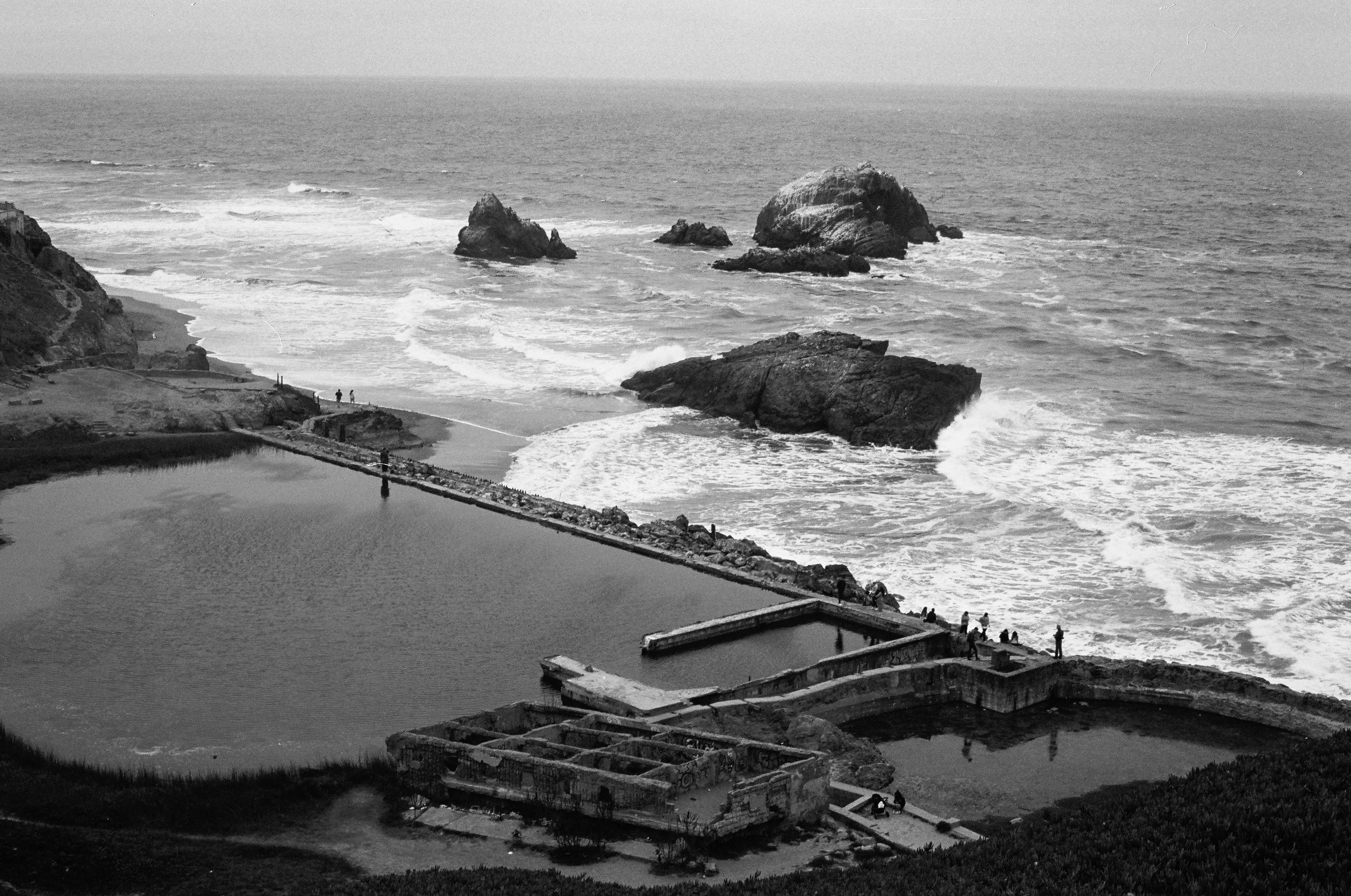 Coastal landscape showing Seal Rocks offshore formations with crashing waves weathered pools and infrastructure overlooking Pacific Ocean