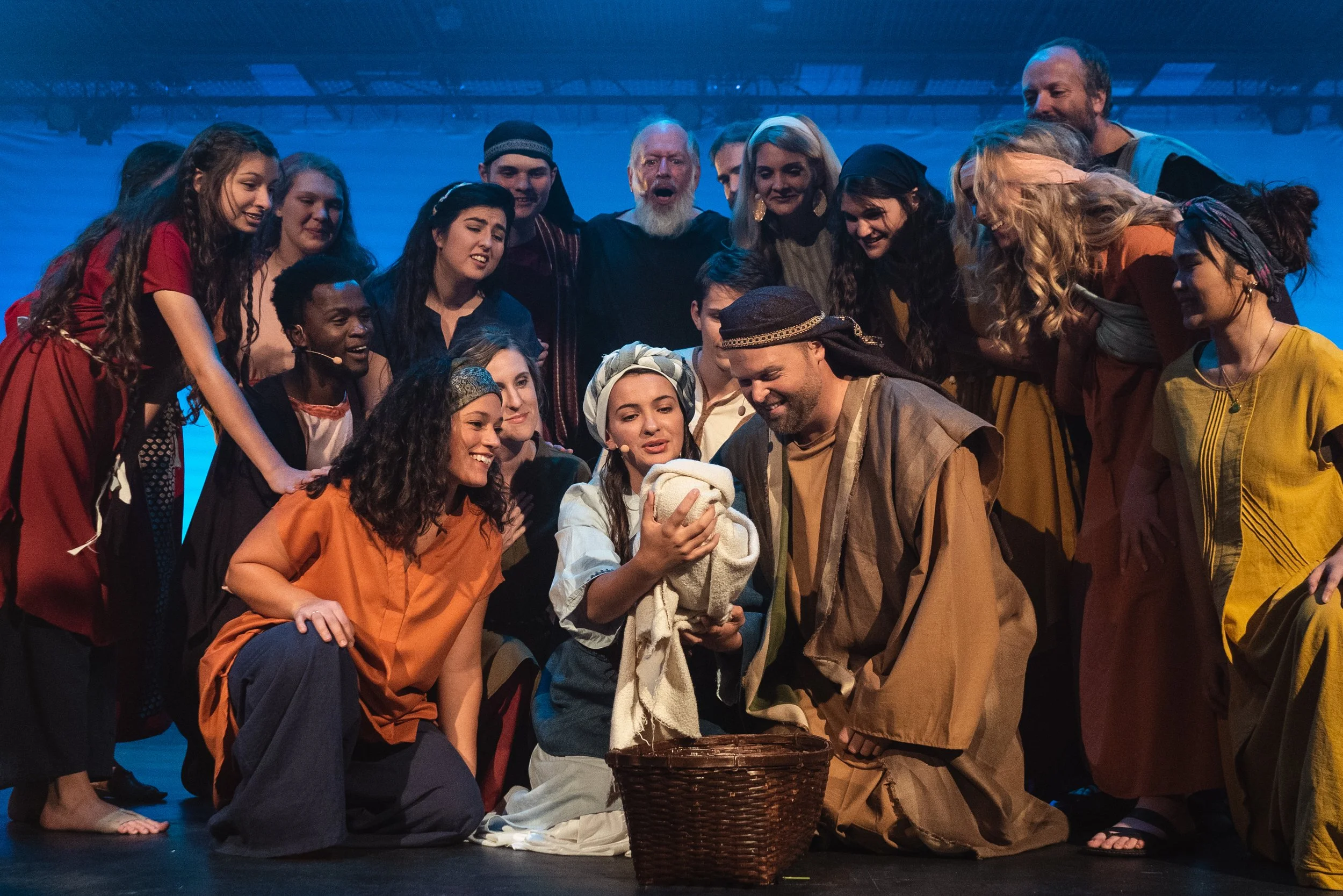 A joyful cast of costumed performers gathered together on stage