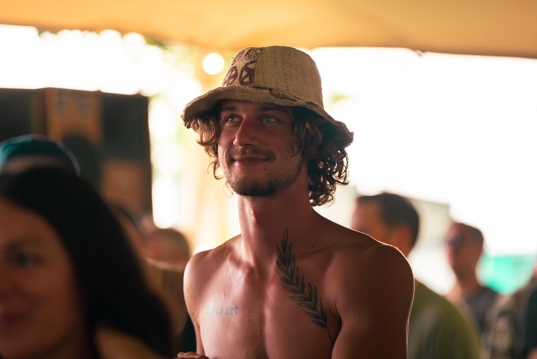 Jongeman met bucket hat en tattoo kijkt omhoog in de tent op Rastaplas 2025