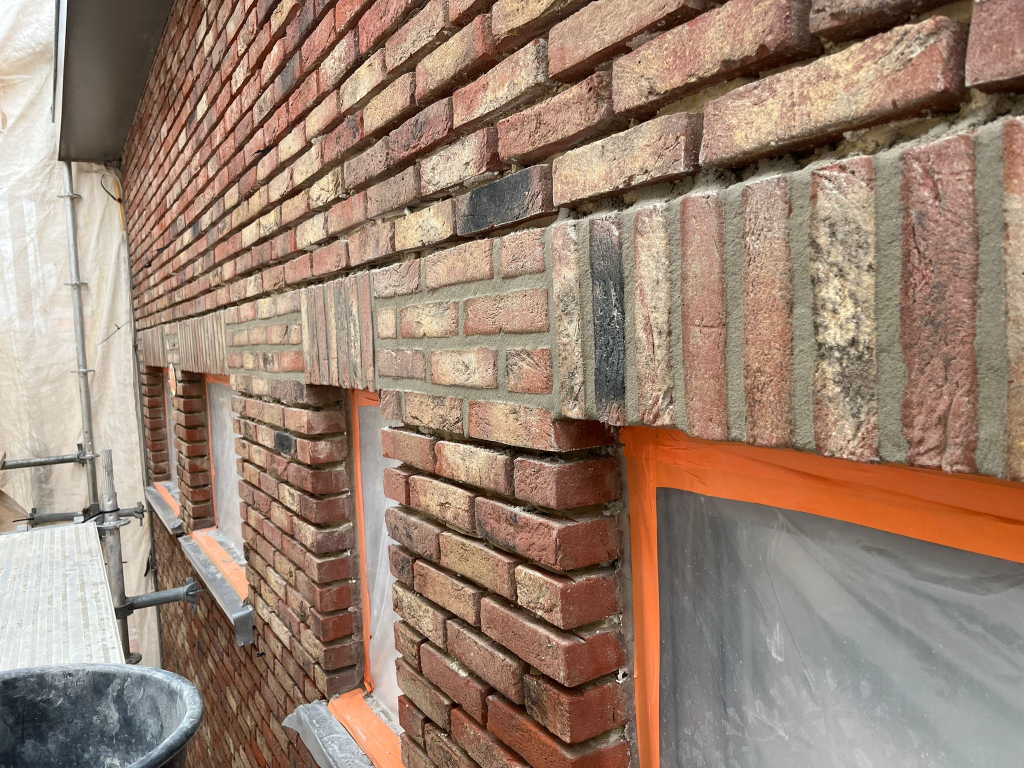 Close-up voegwerk met oranje afplaktape op stelling