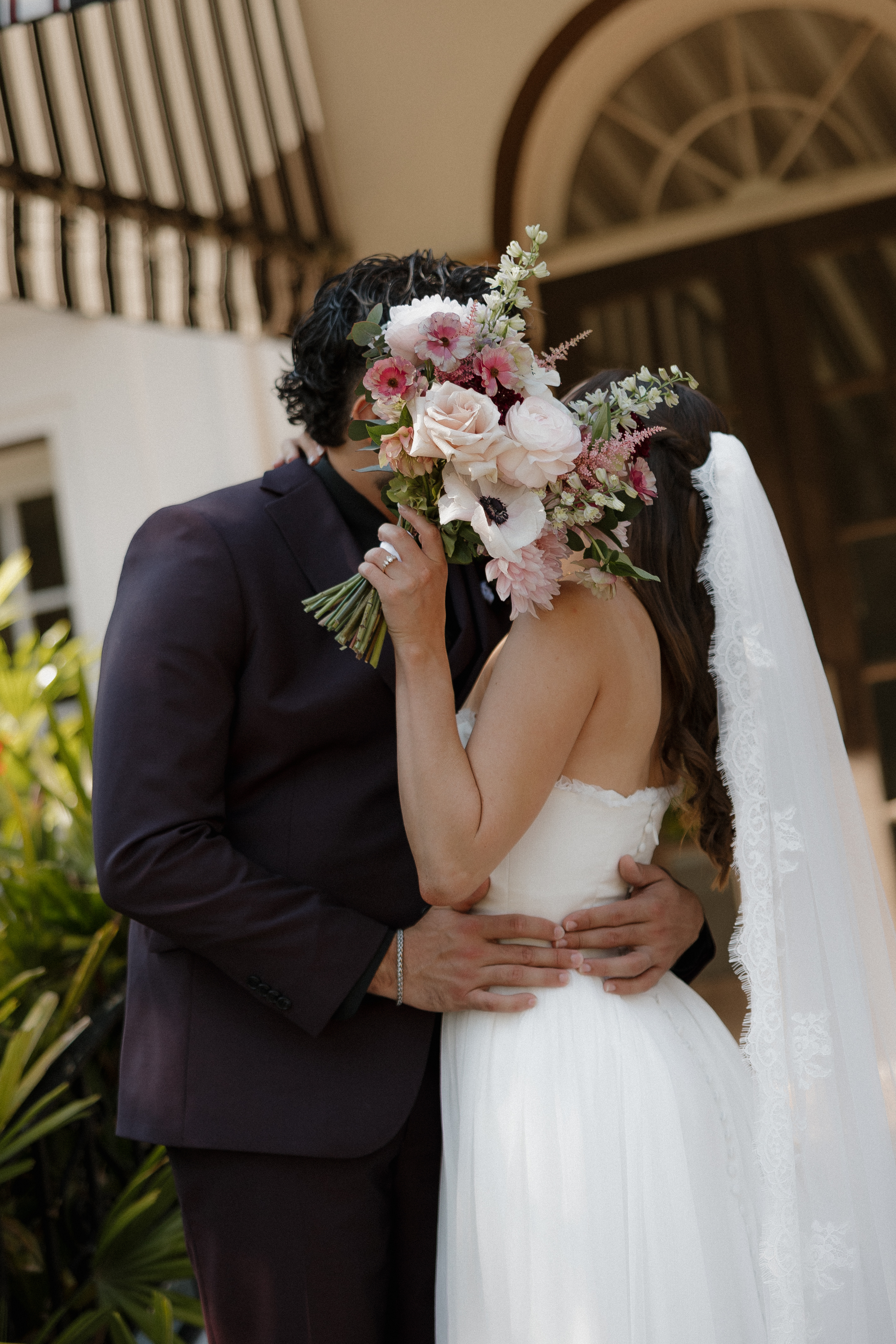 Bride and groom kissing behind a beautiful floral bouquet