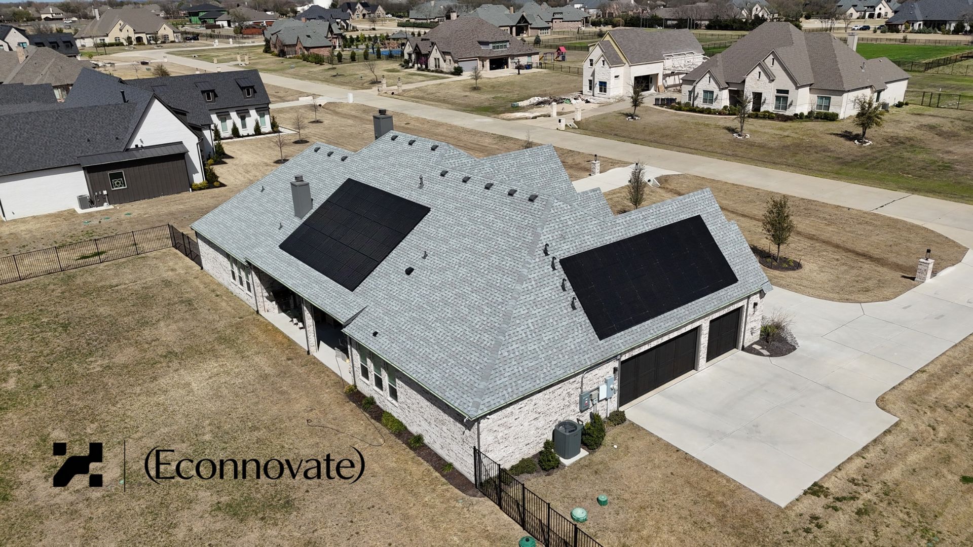 Aerial view of a residential home with black solar panels installed on roof