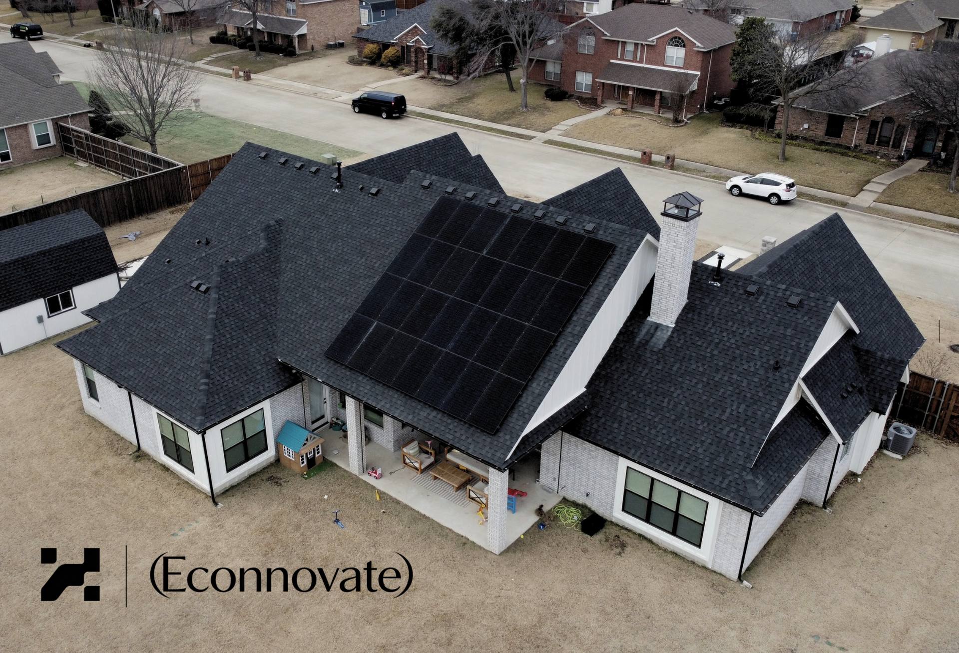 Aerial view of a residential home with solar panels on peaked roof