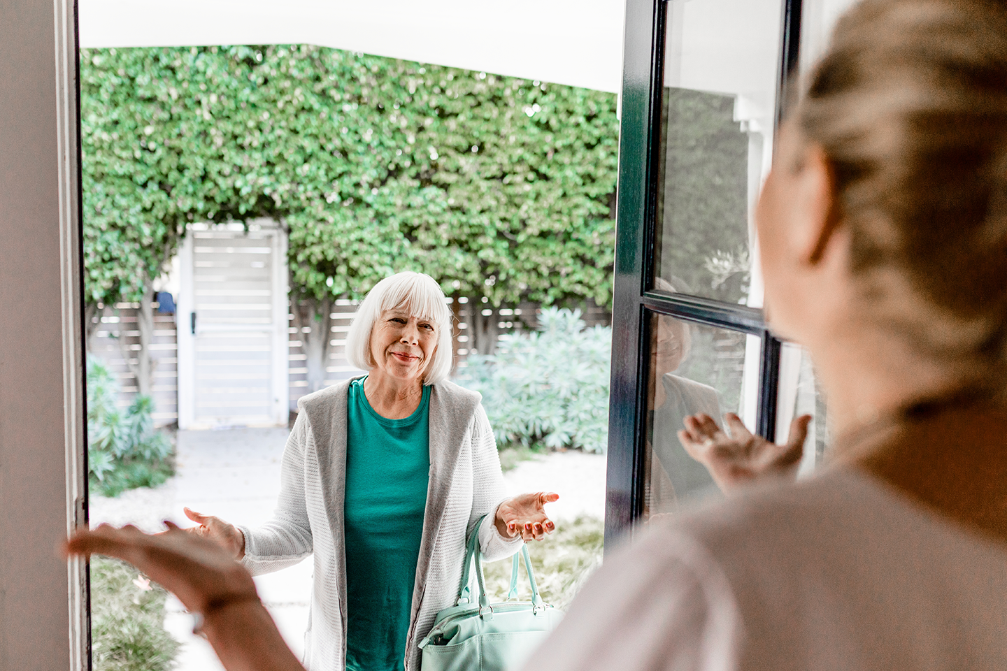Senior woman warmly greeting at her doorway