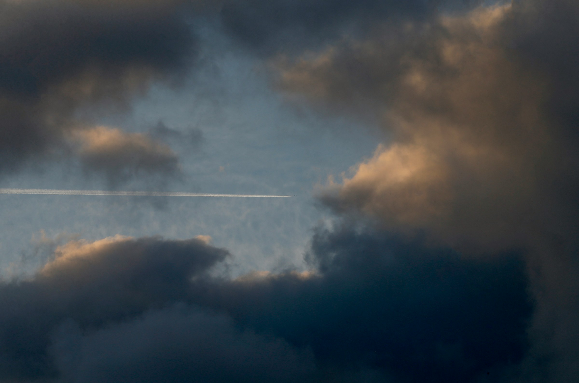 Dramatic cloudscape with jet contrail cutting through at sunset