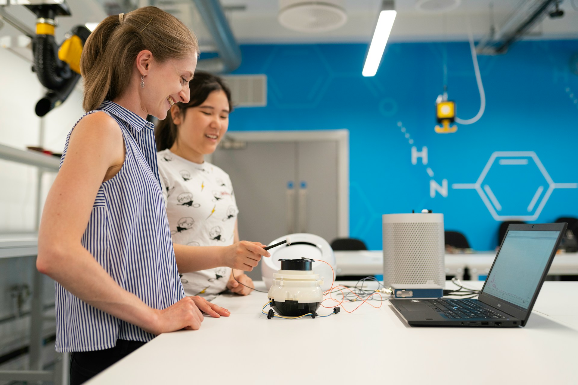 Two researchers working in a modern flexible lab space with blue walls and molecular diagrams