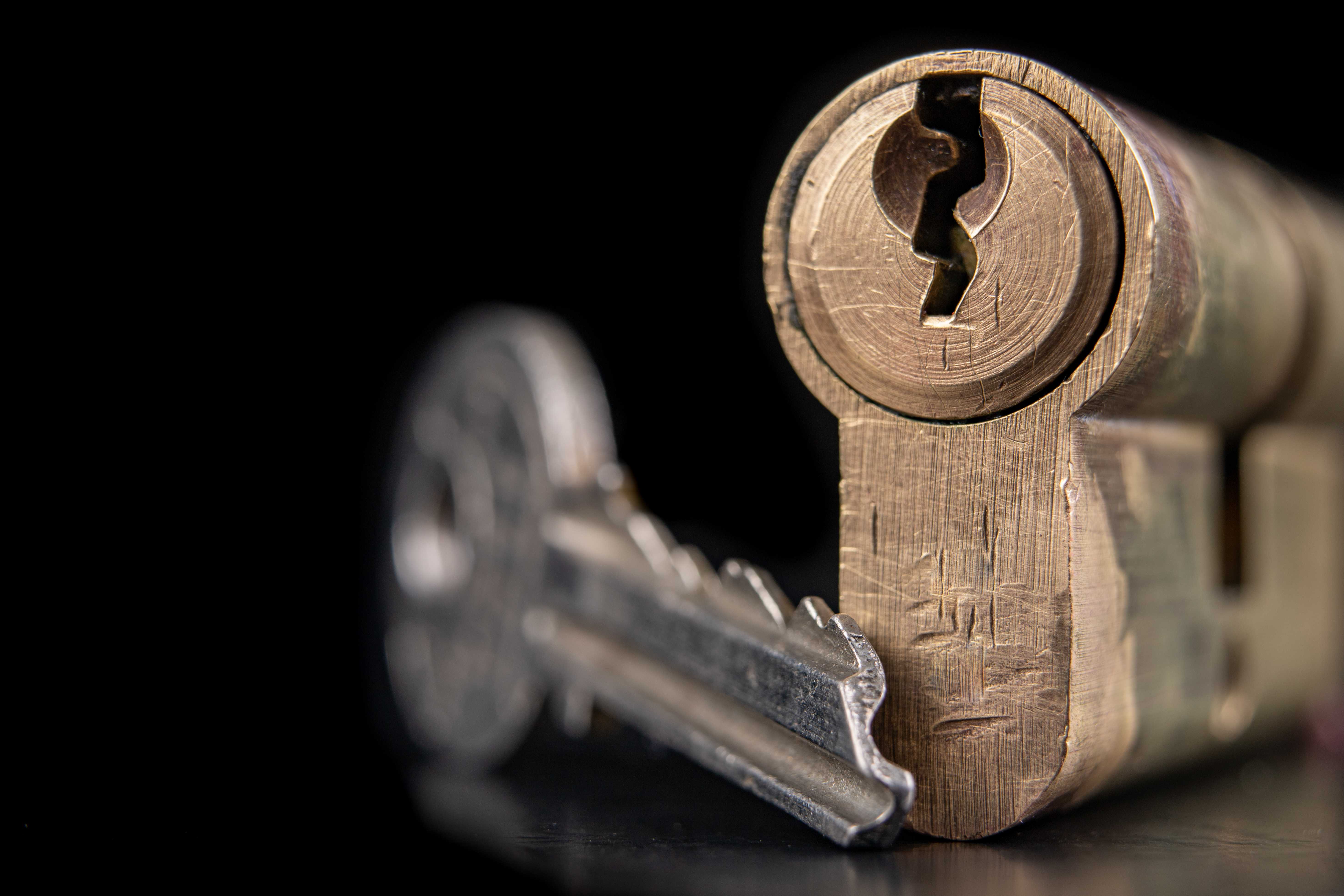 Close-up of a key beside a worn lock cylinder