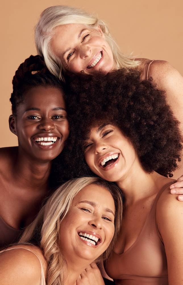 Four women of diverse ages and skin tones smiling together