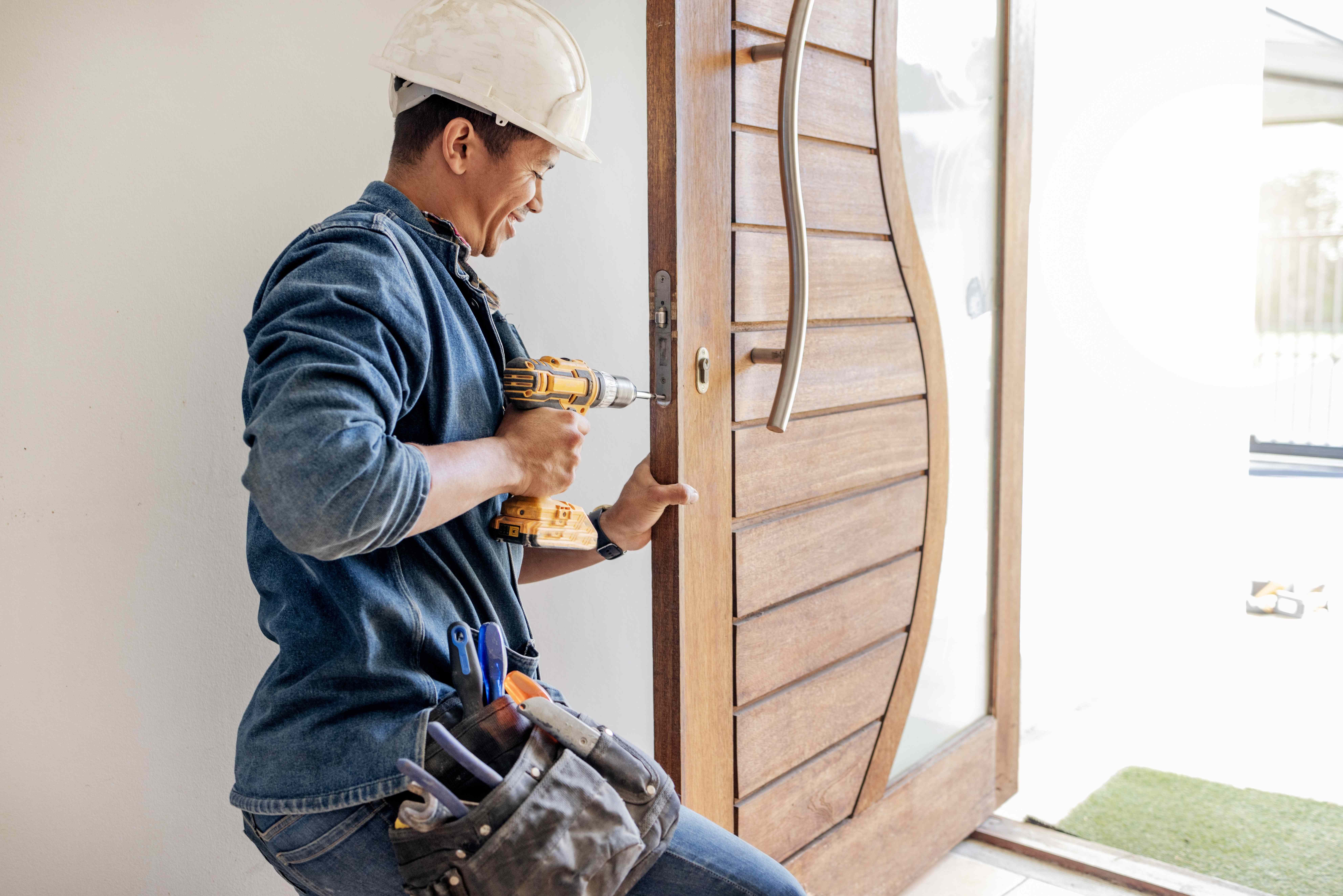 Technician drilling into a wooden front door