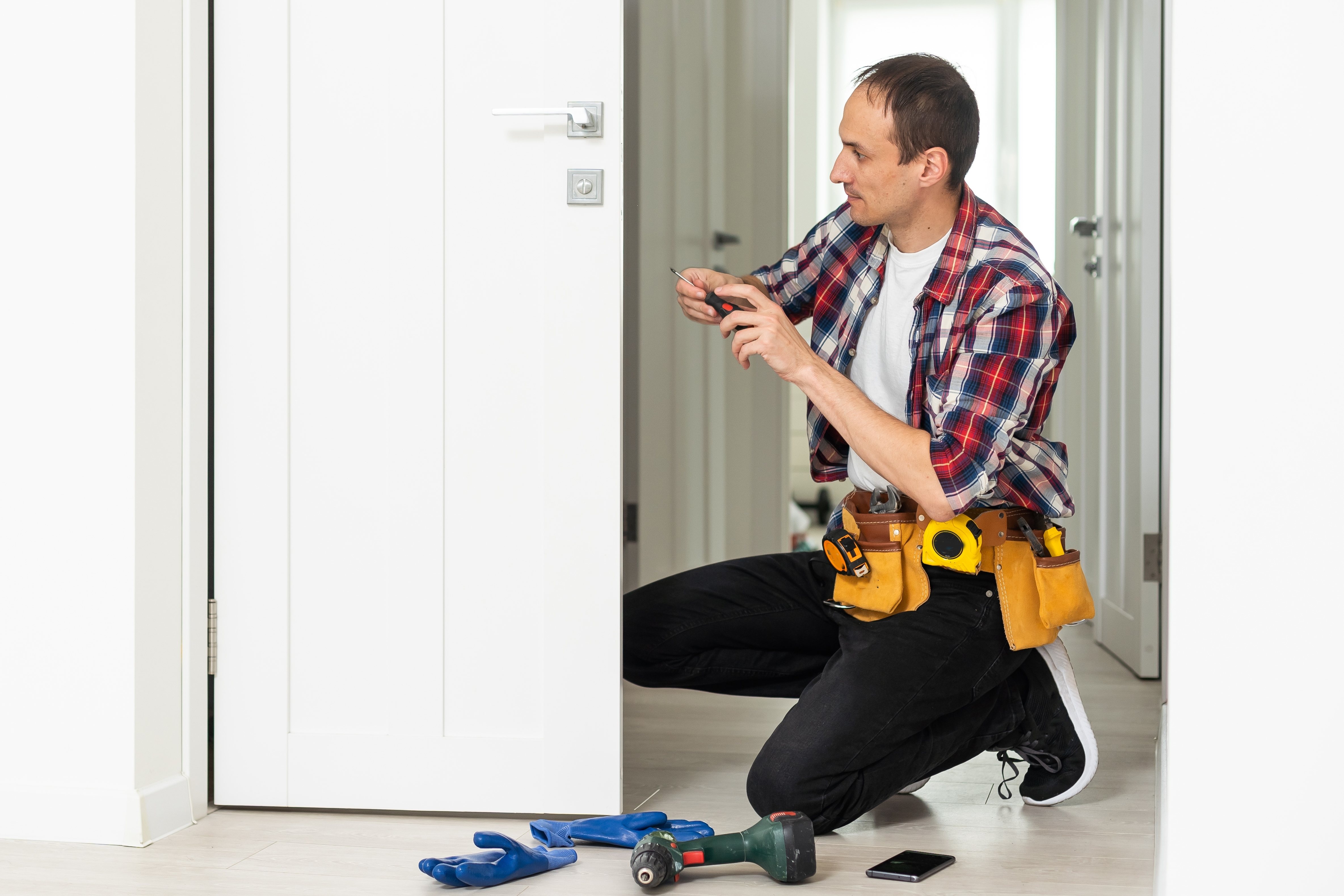Locksmith working on the lock of a white door