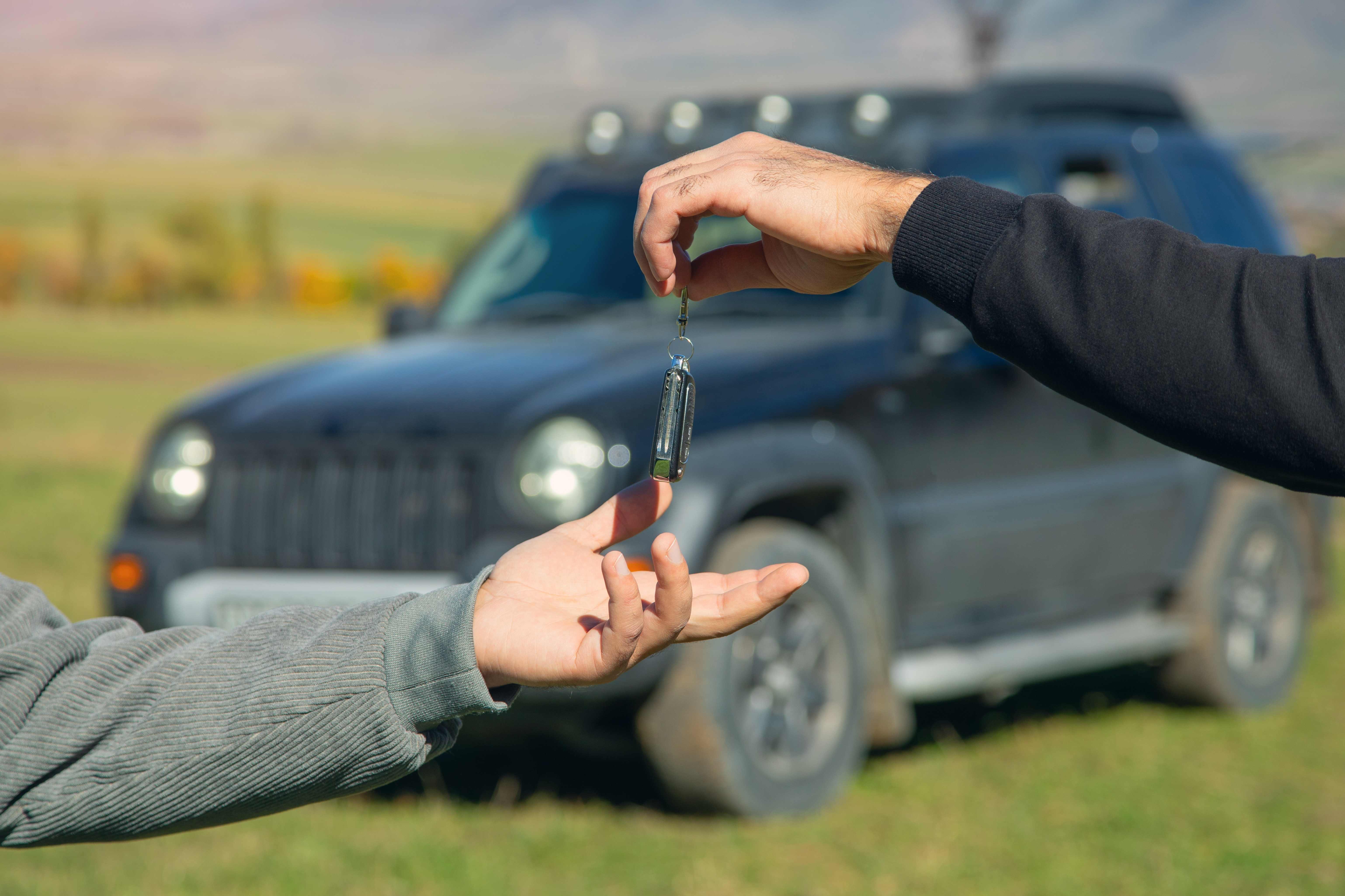 Handing car keys to a customer beside a vehicle