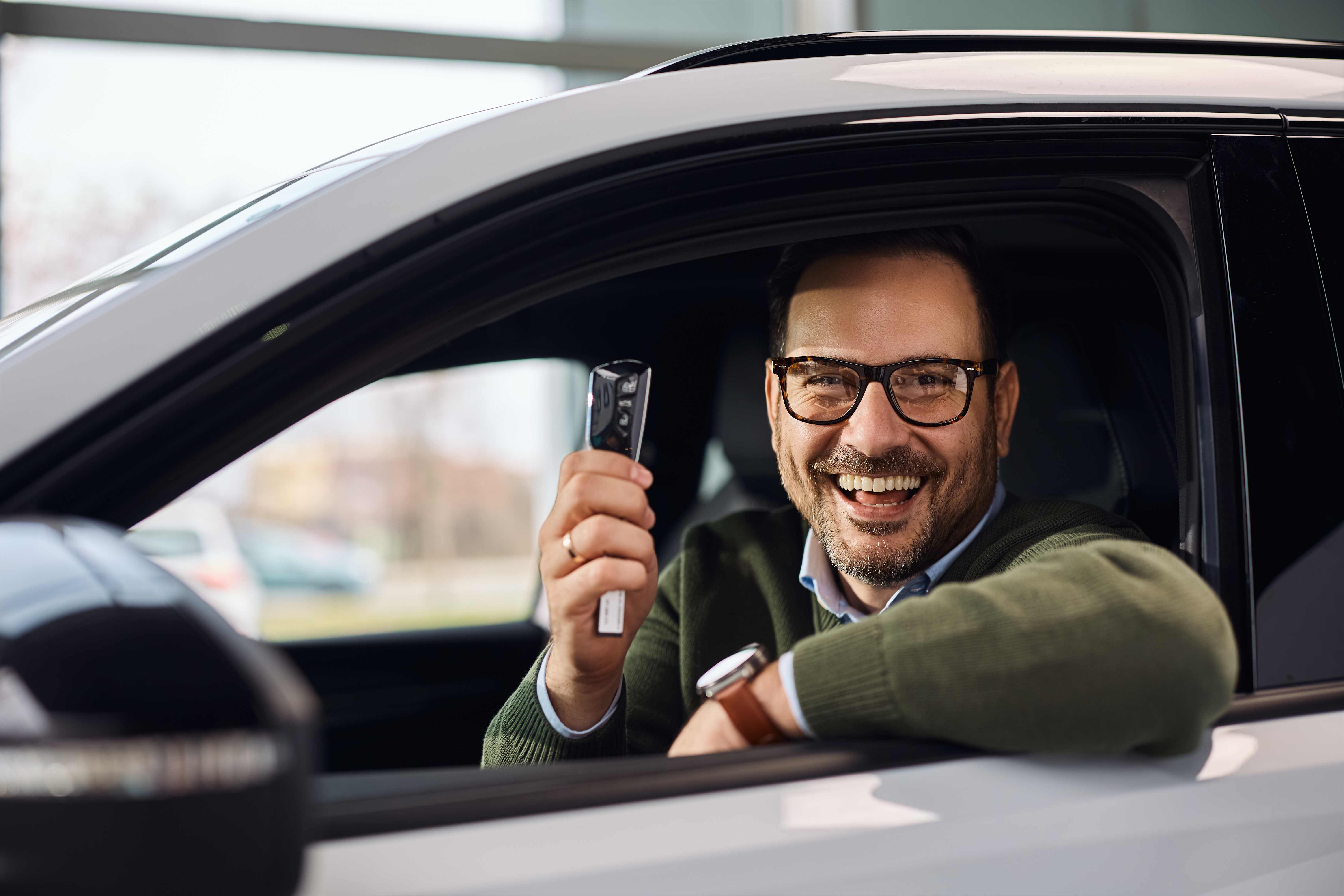 Smiling driver holding a car key remote