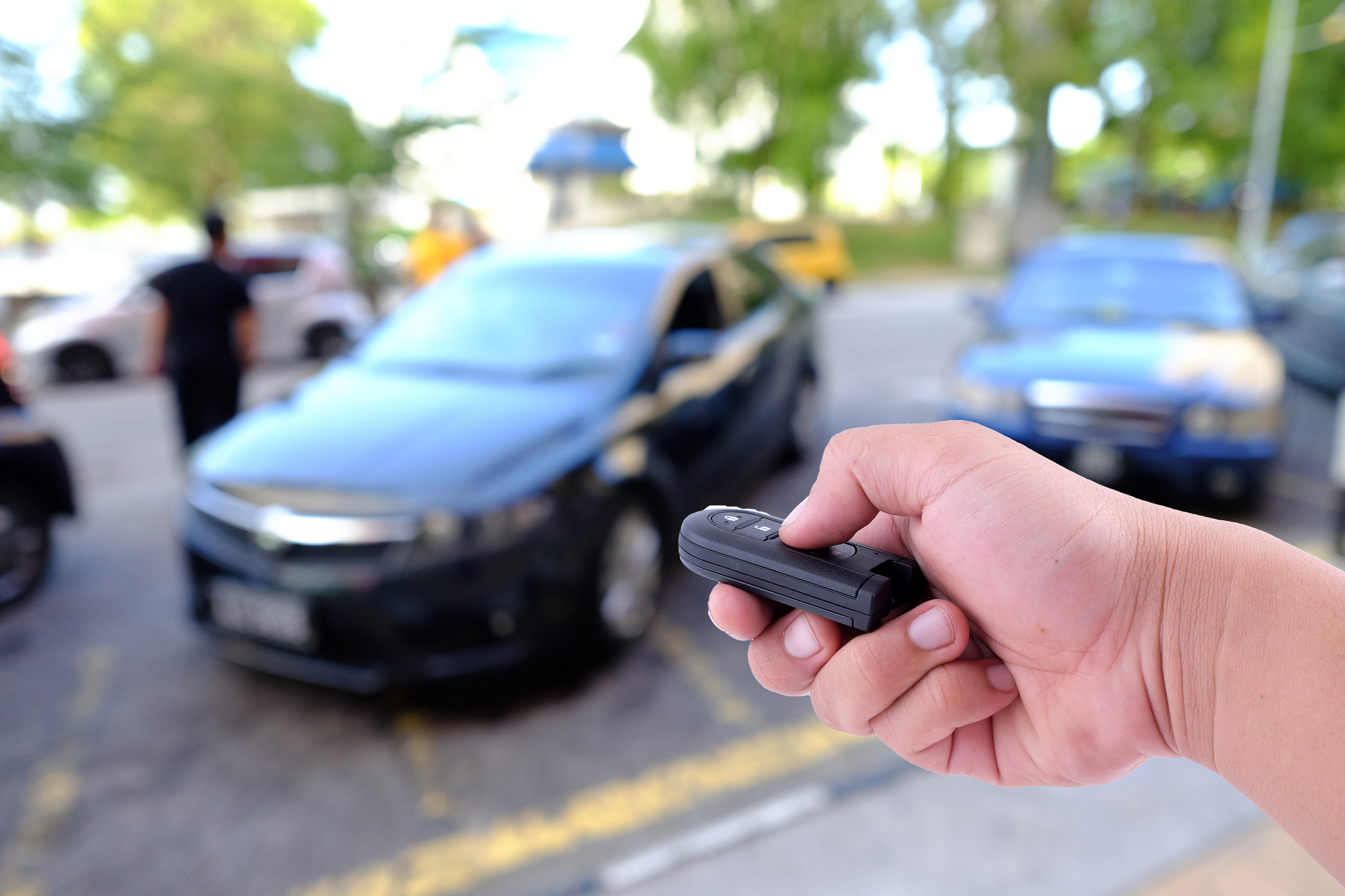 Car key fob held beside a parked car