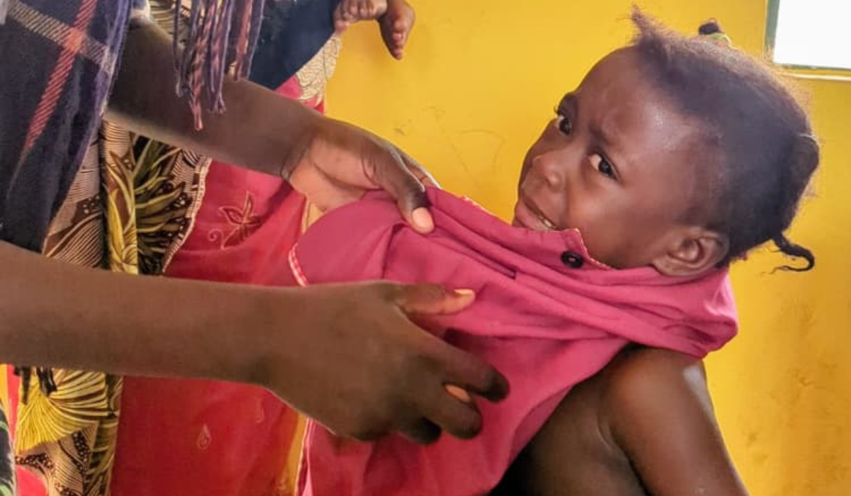 Baby in pink clothing being held by caregiver