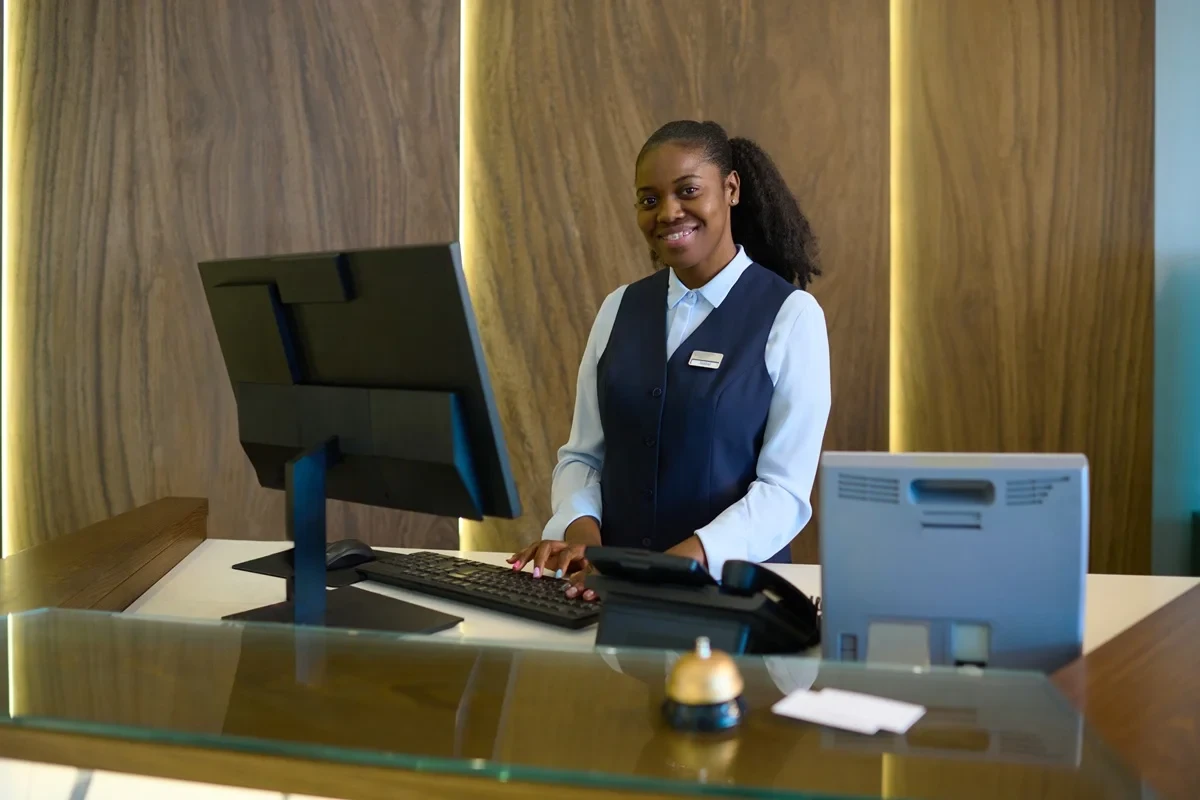 Recepcionista profissional e sorridente no balcão de trabalho com computador moderno