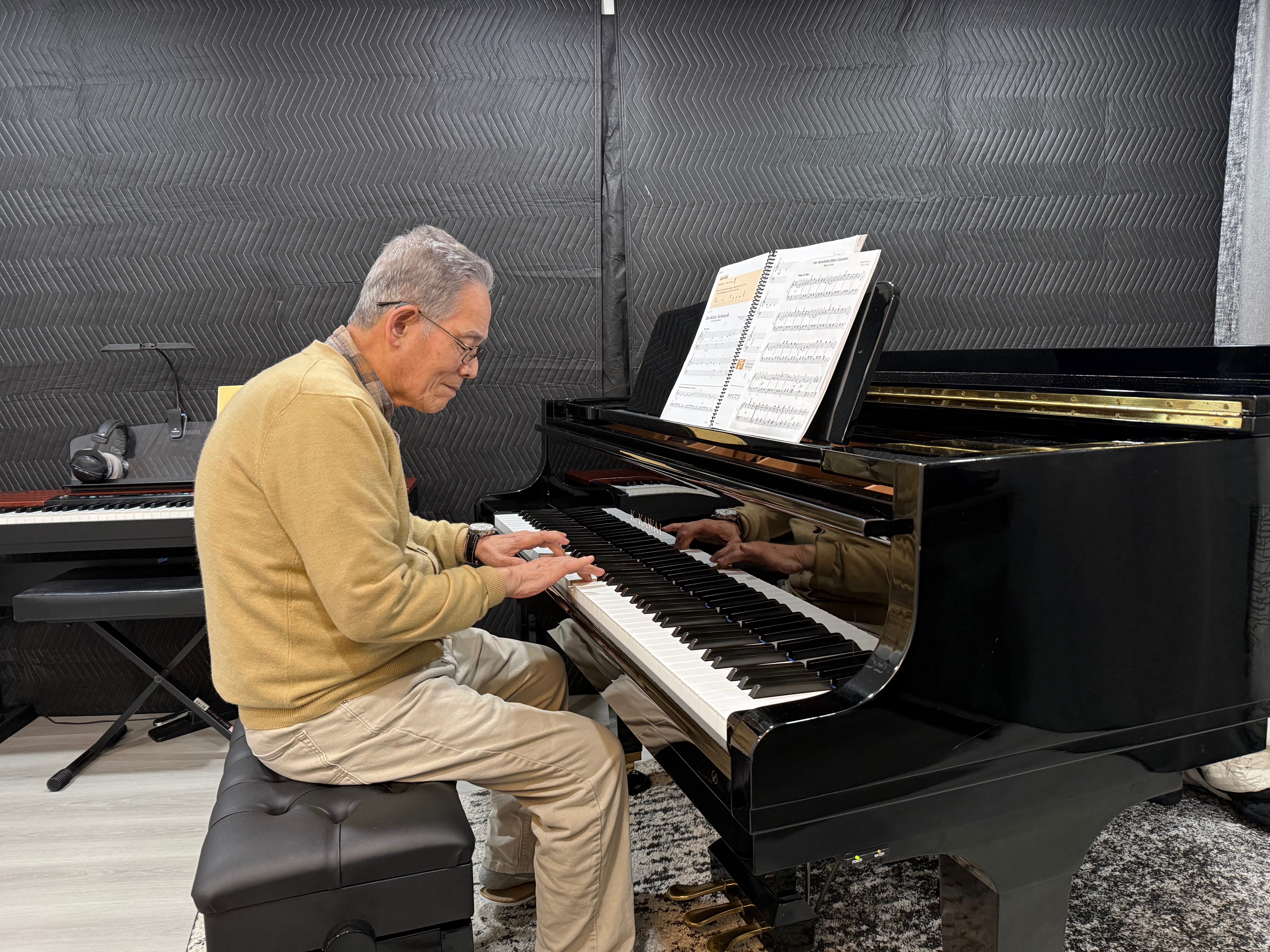 Adult student playing grand piano during a lesson