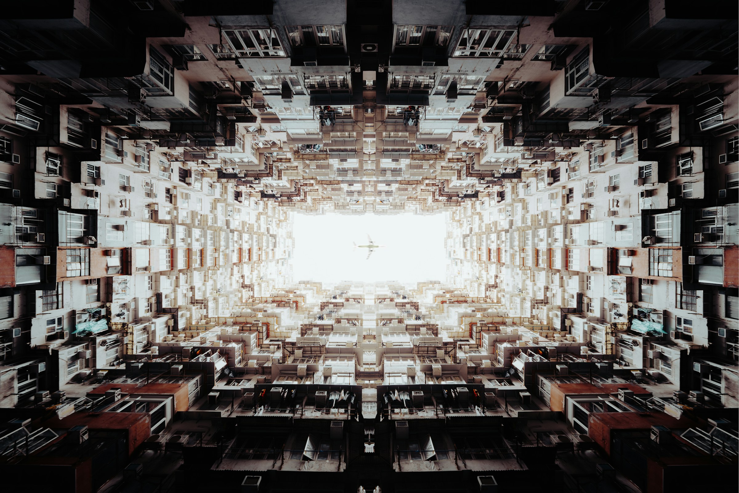 Looking up at dense urban apartment buildings forming a symmetrical rectangular opening to the sky