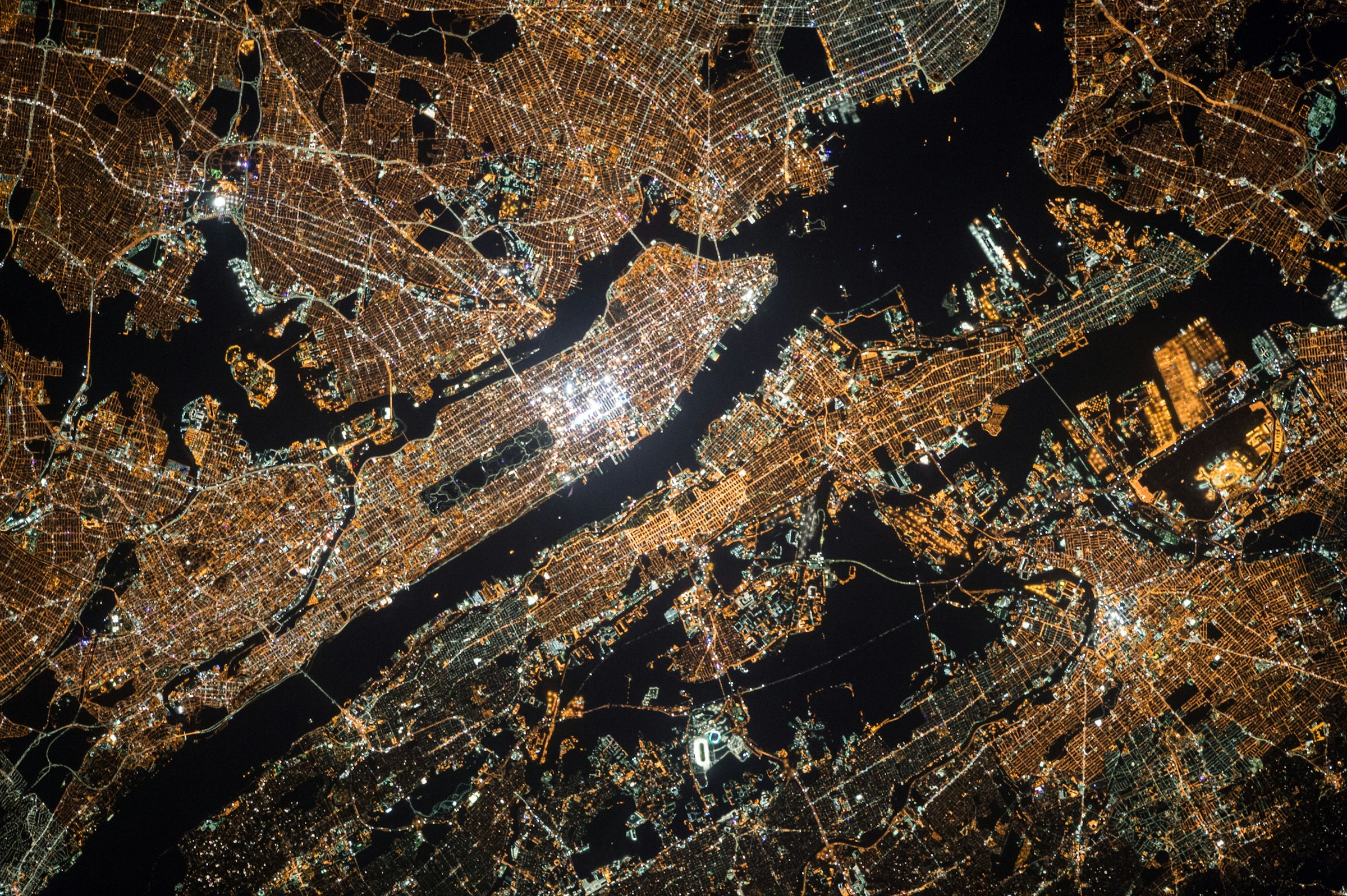 Aerial night view of New York City showing Manhattan and surrounding boroughs with city lights