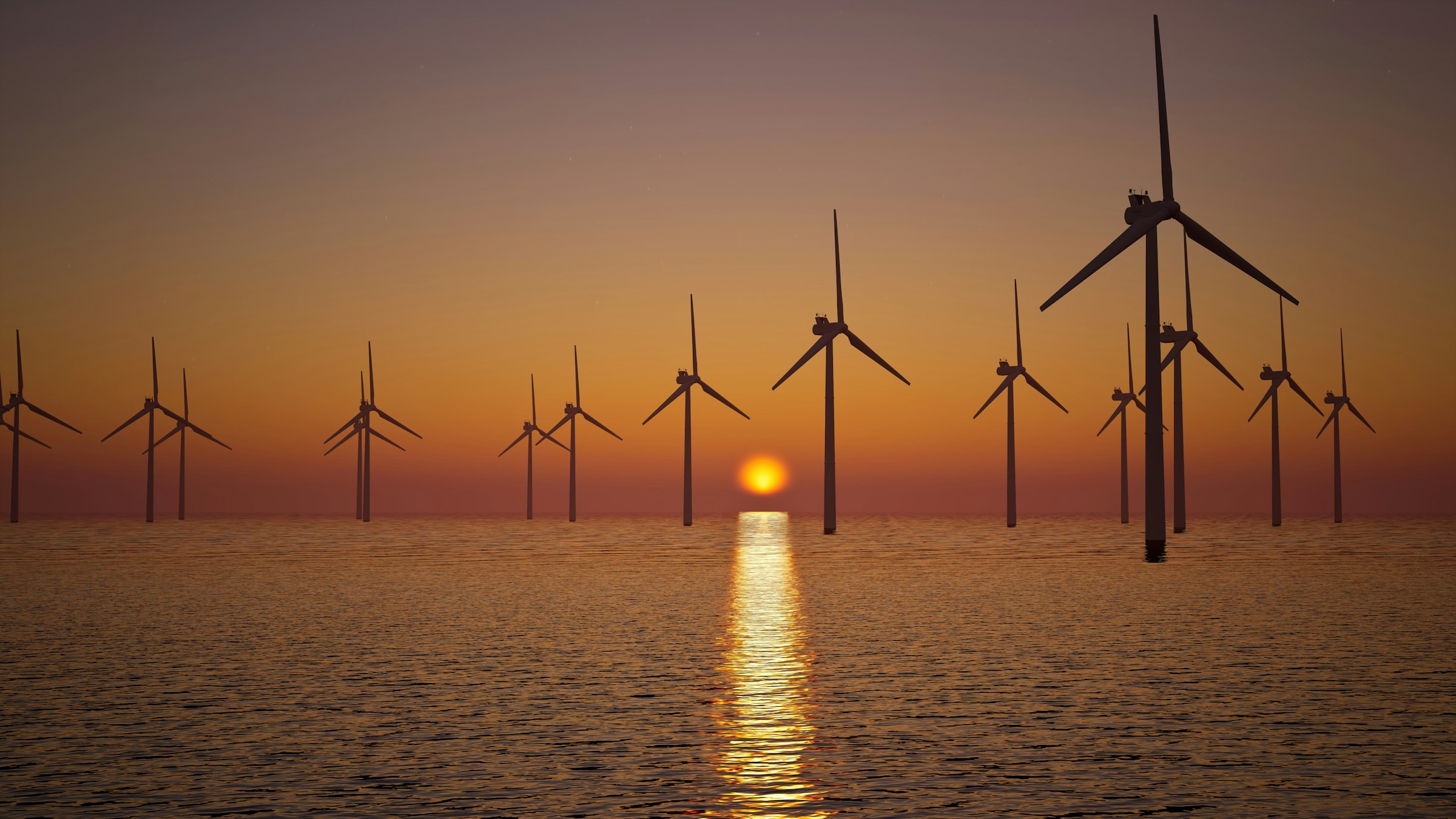 Offshore wind farm at sunset with turbines silhouetted against orange sky