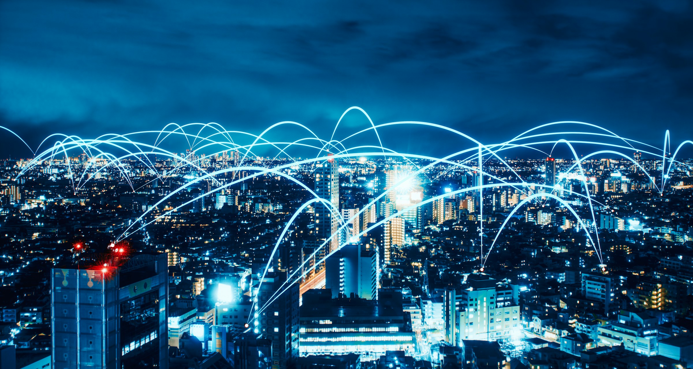 Night cityscape with digital light arcs representing smart city connectivity