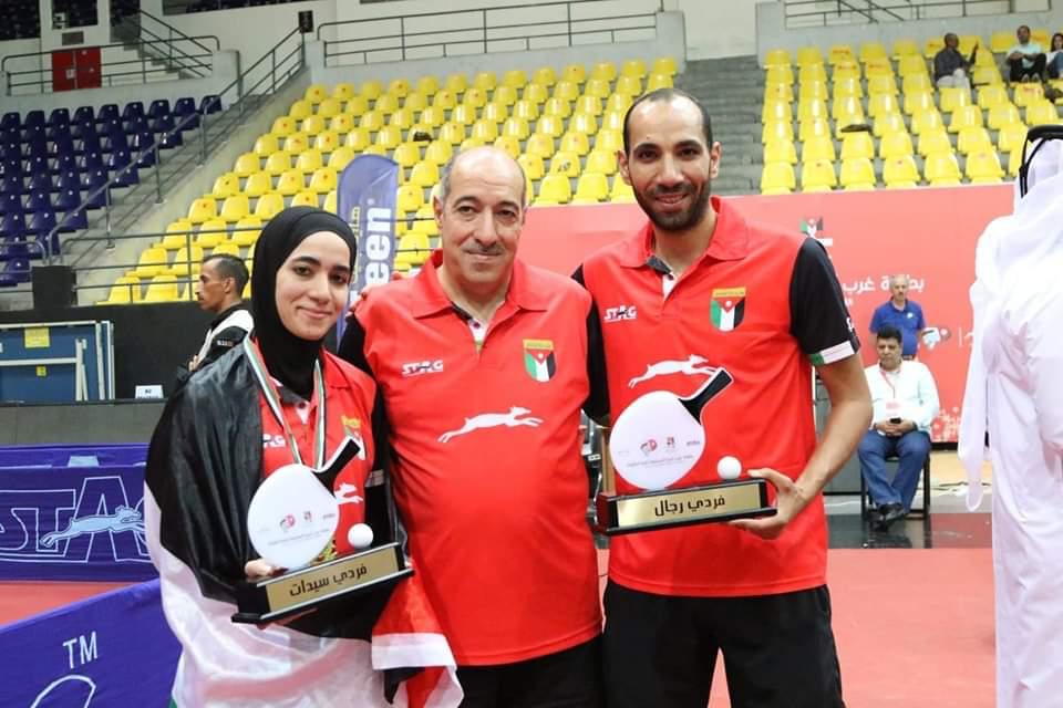 Taima Abu Yaman with her brother Zaid after a tournament, holding singles trophies