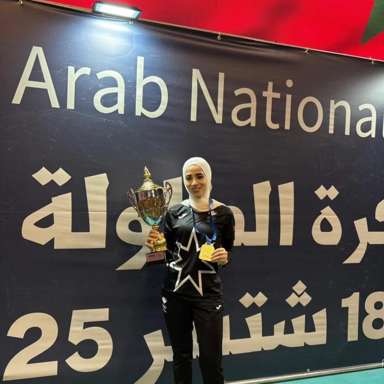 Taima Abu Yaman holding a gold medal and trophy at the Arab Nationals in Morocco