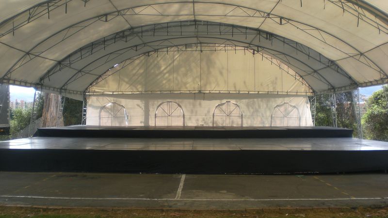 Tarima negra instalada bajo carpa transparente en terreno abierto con estructura de marcos