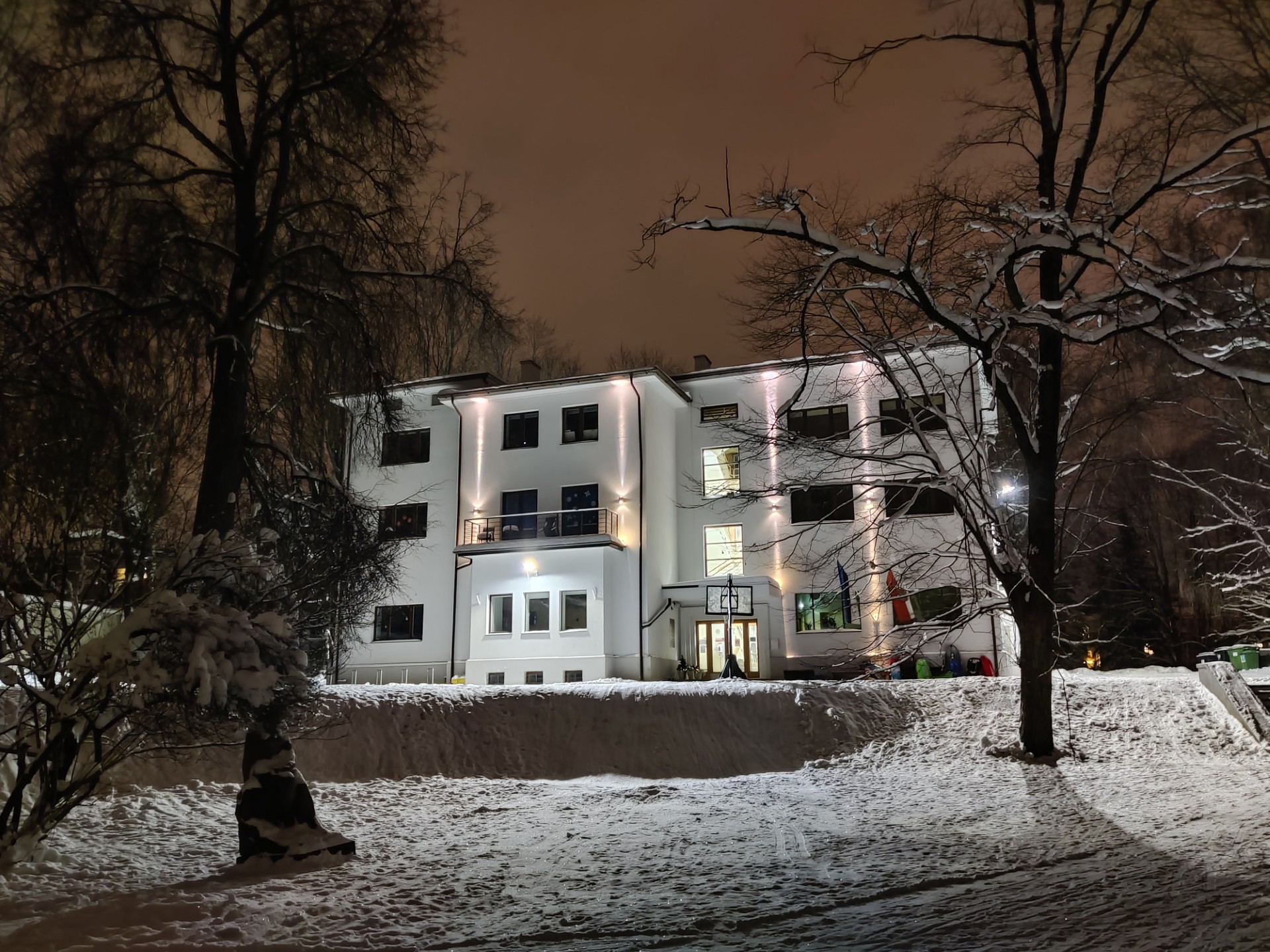 Tartu International School - edificio iluminado en una noche de invierno con nieve