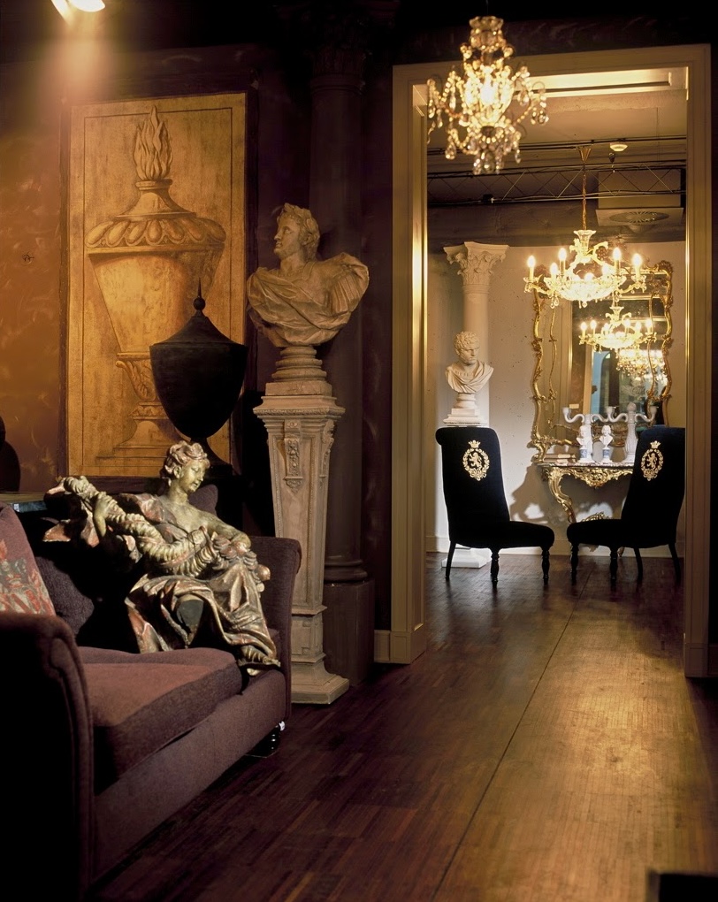 A moody showroom blending classical sculpture, hand-painted panels, and candlelit ambiance.
