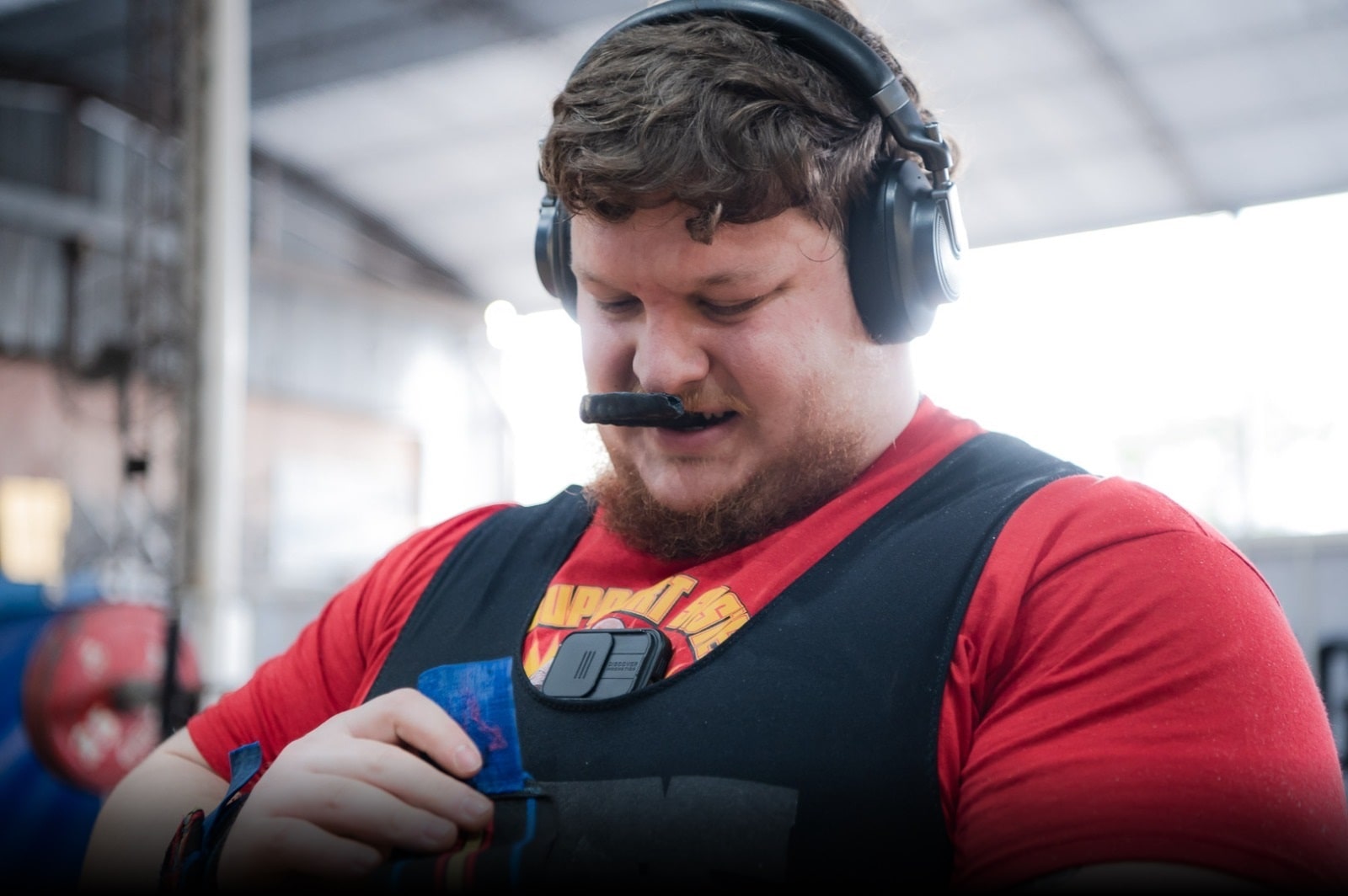 Franco Jose Leo Menazzi (Big Tilo) preparándose intensamente para una competencia de powerlifting, con auriculares y mordedor