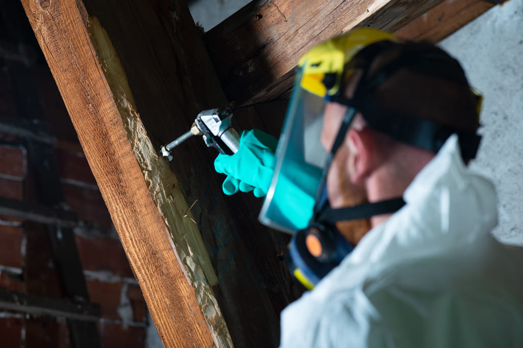 Technicien ACO-Habitat injectant produit de traitement dans poutre