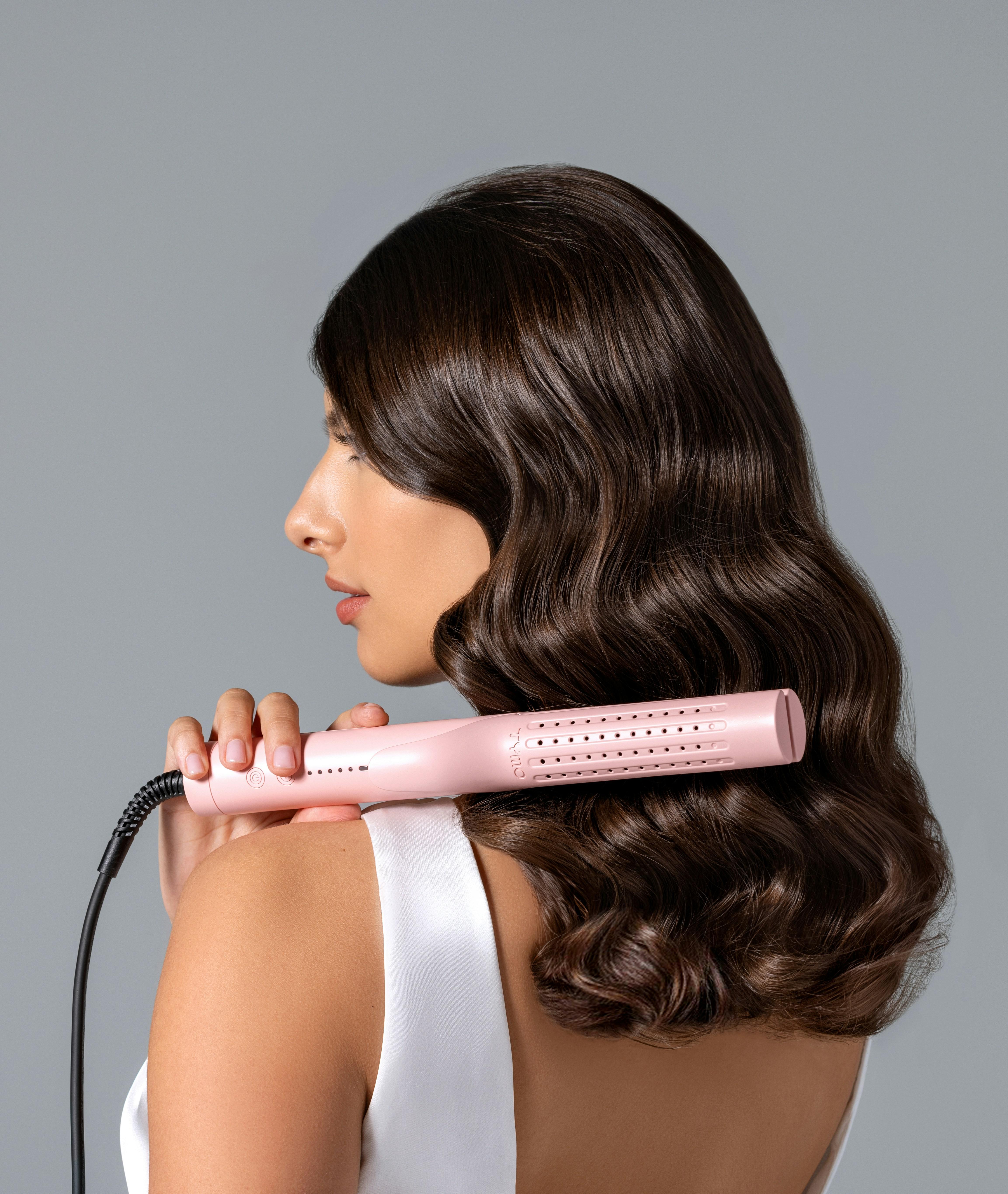 Woman with beautiful wavy hair holding a hair dryer