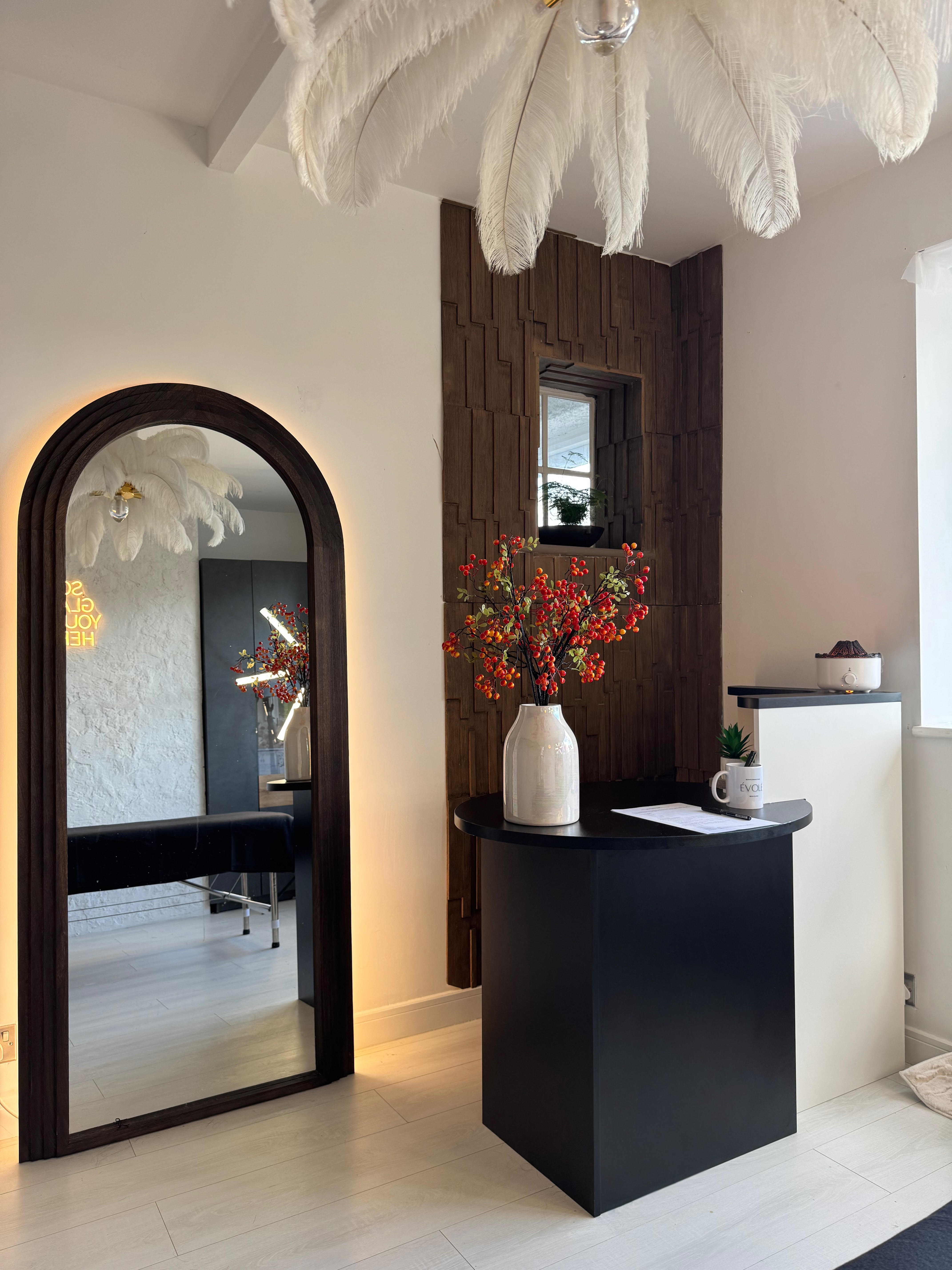 Évolé Massage Clinic reception area with elegant feather chandelier and neon welcome sign