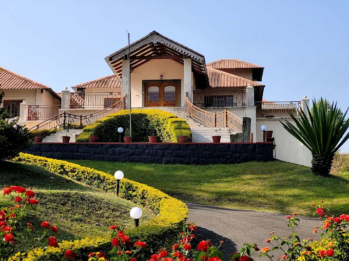 Tea County cottage framed by sculpted gardens and red flowers