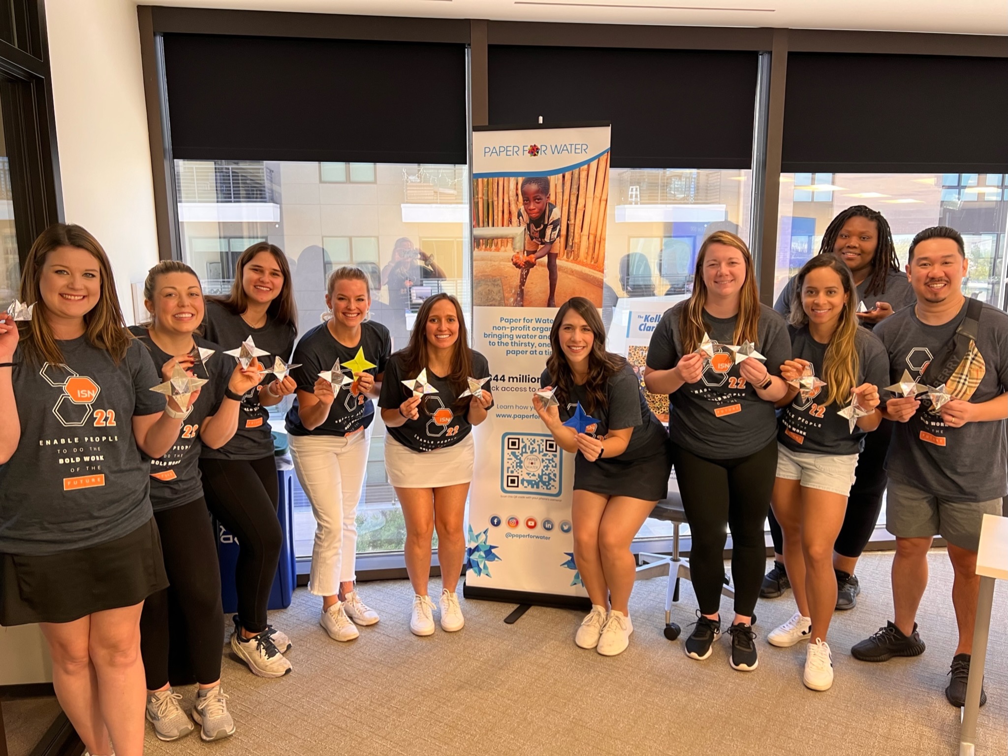 Large team of diverse volunteers with Paper for Water origami