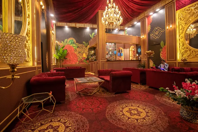 Opulent lounge with red velvet sofas, gold panelling, and a crystal chandelier