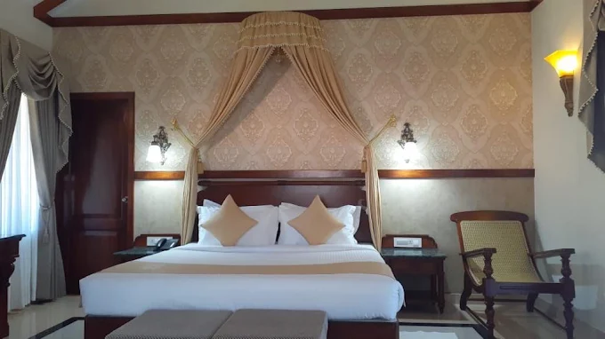 Superior Room with a spacious bed, soft curtains, and warm patterned walls