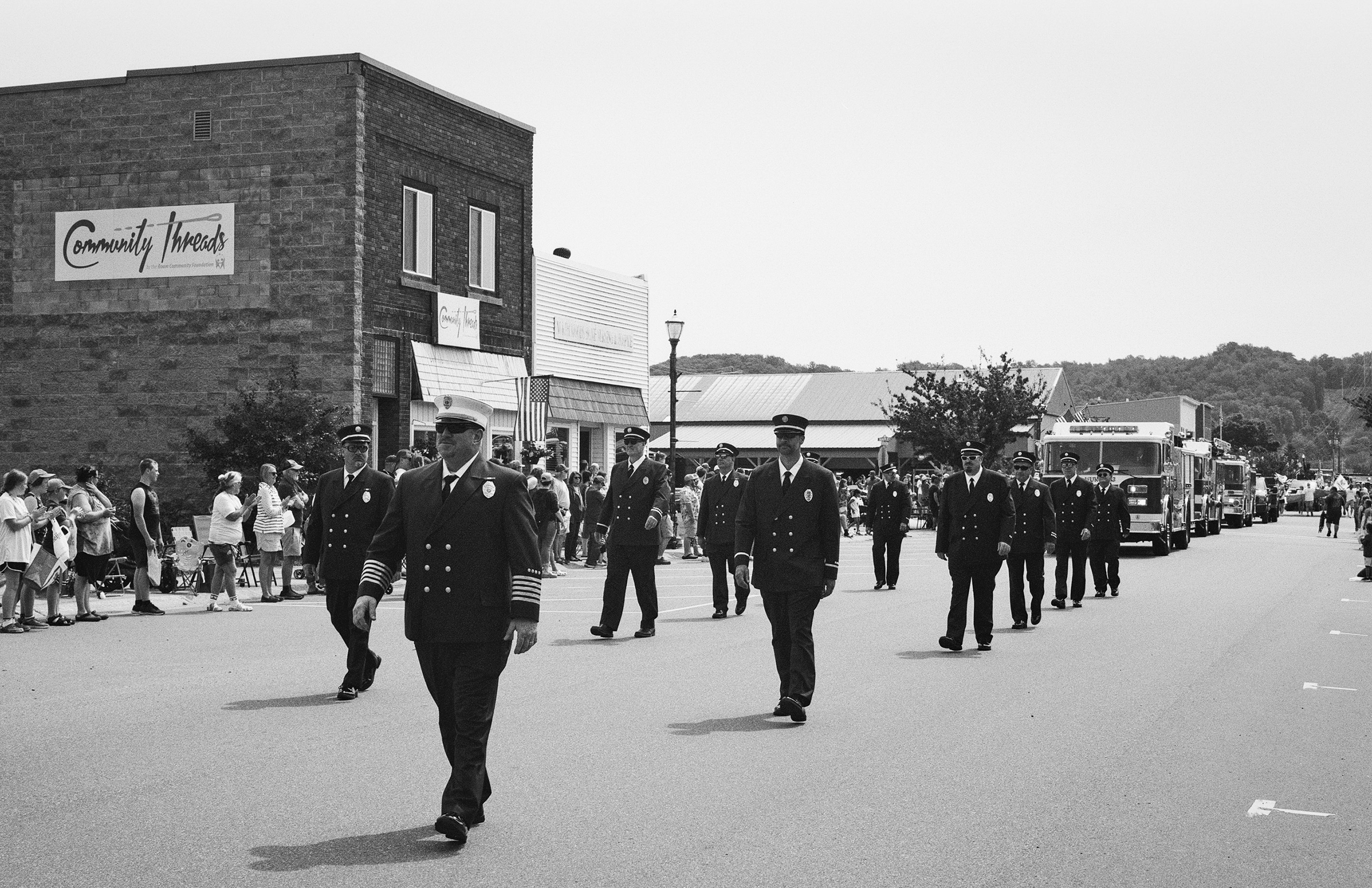 Community Threads building with firefighters marching in uniform during parade