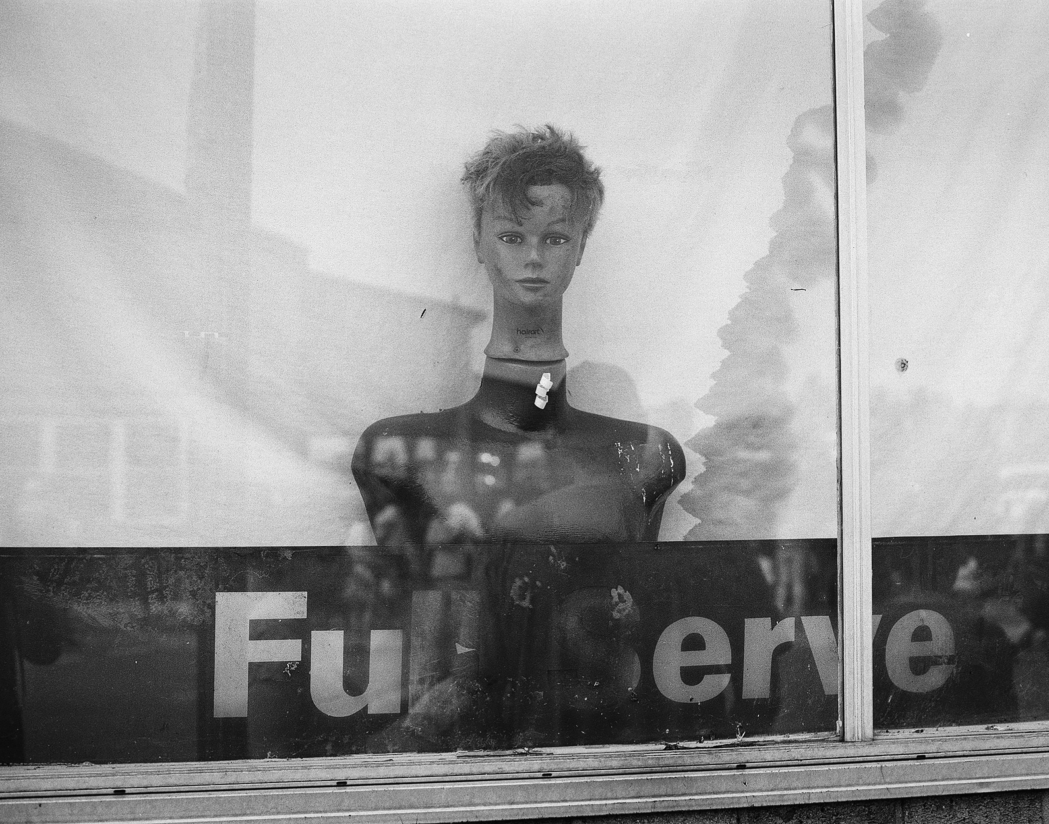 Shop window display with mannequin wearing dark clothing