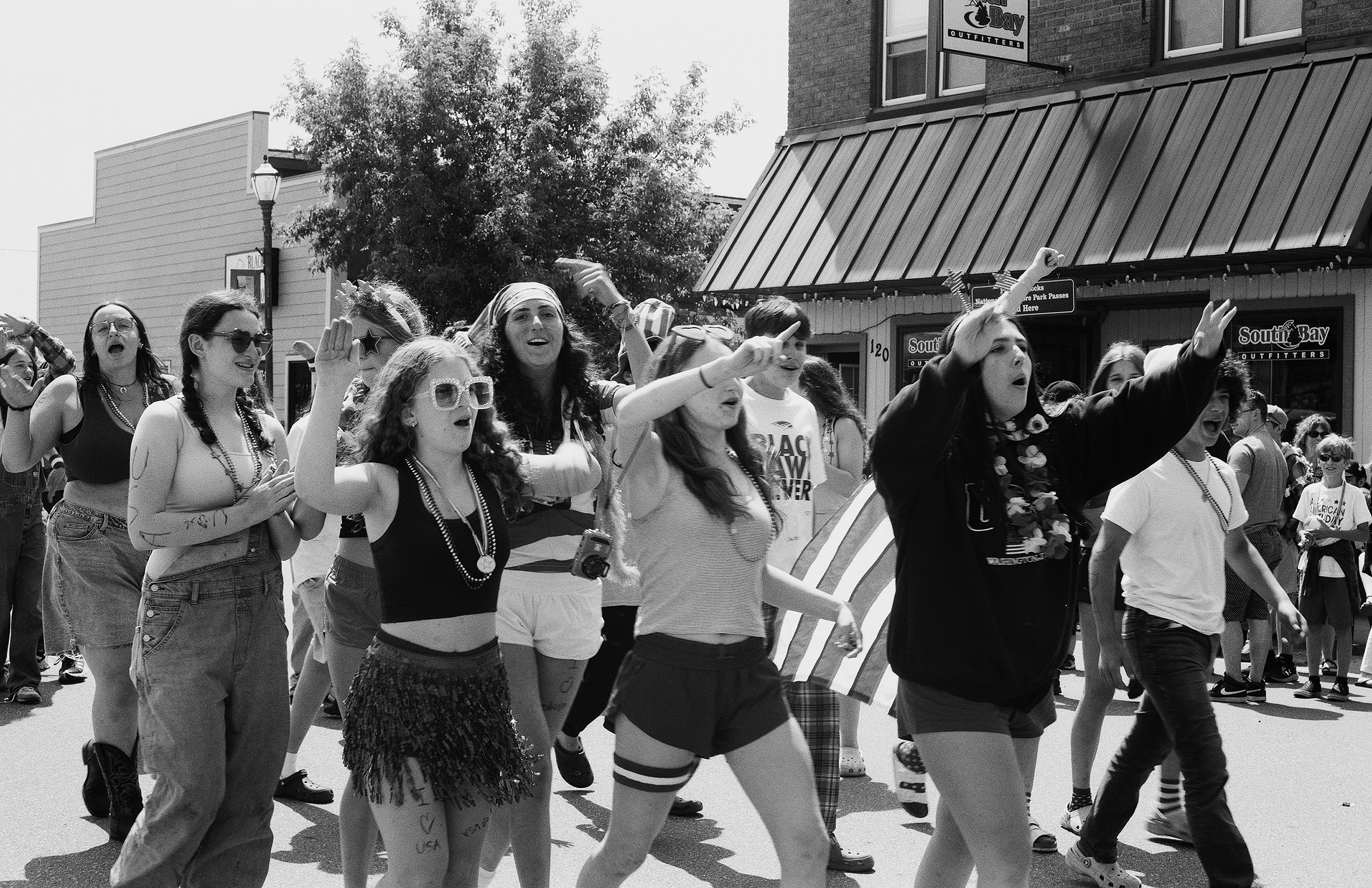 Women in costume beads and festive attire dancing and celebrating on street