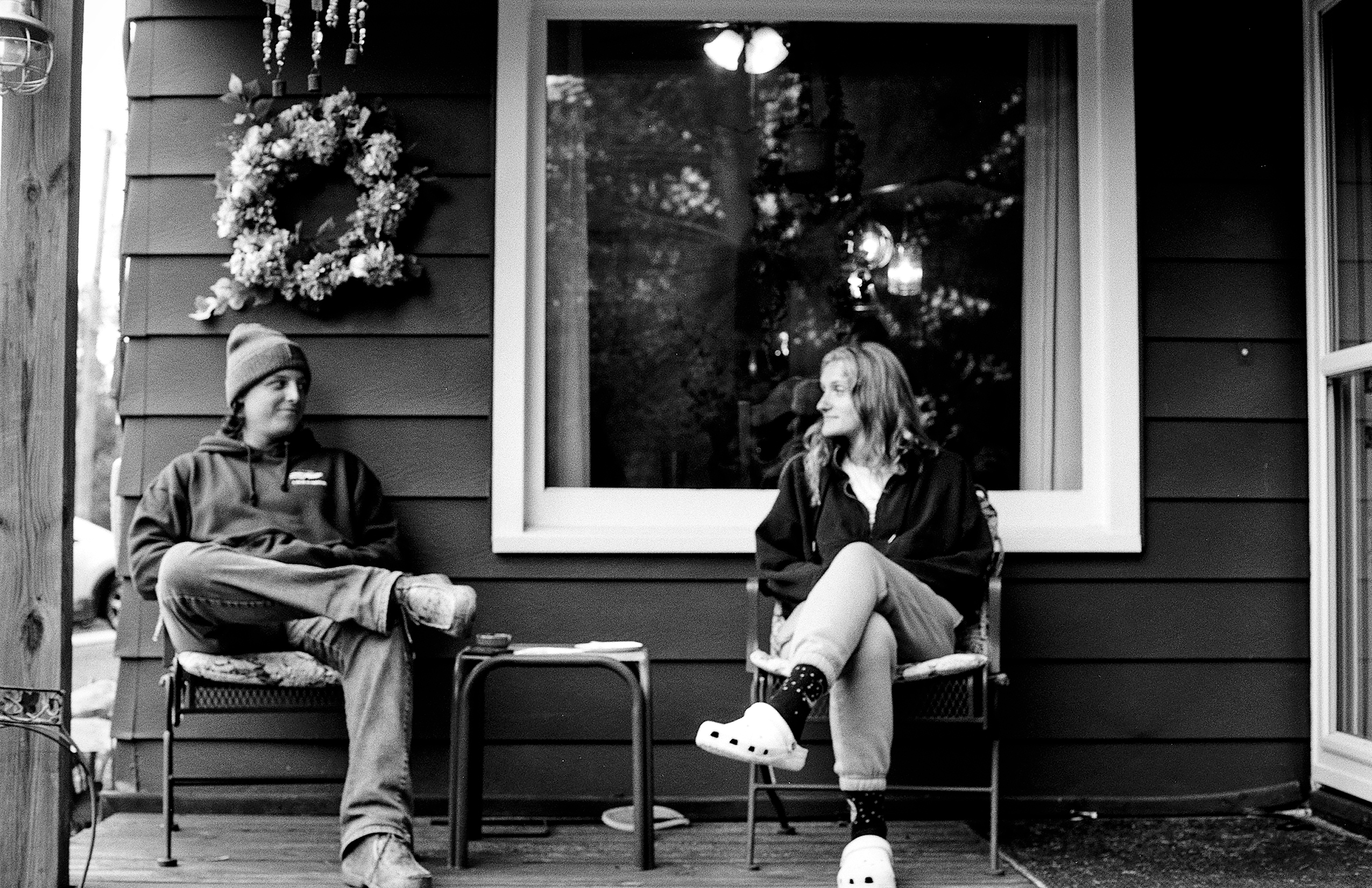 Couple sitting on storefront bench with holiday wreath hanging above