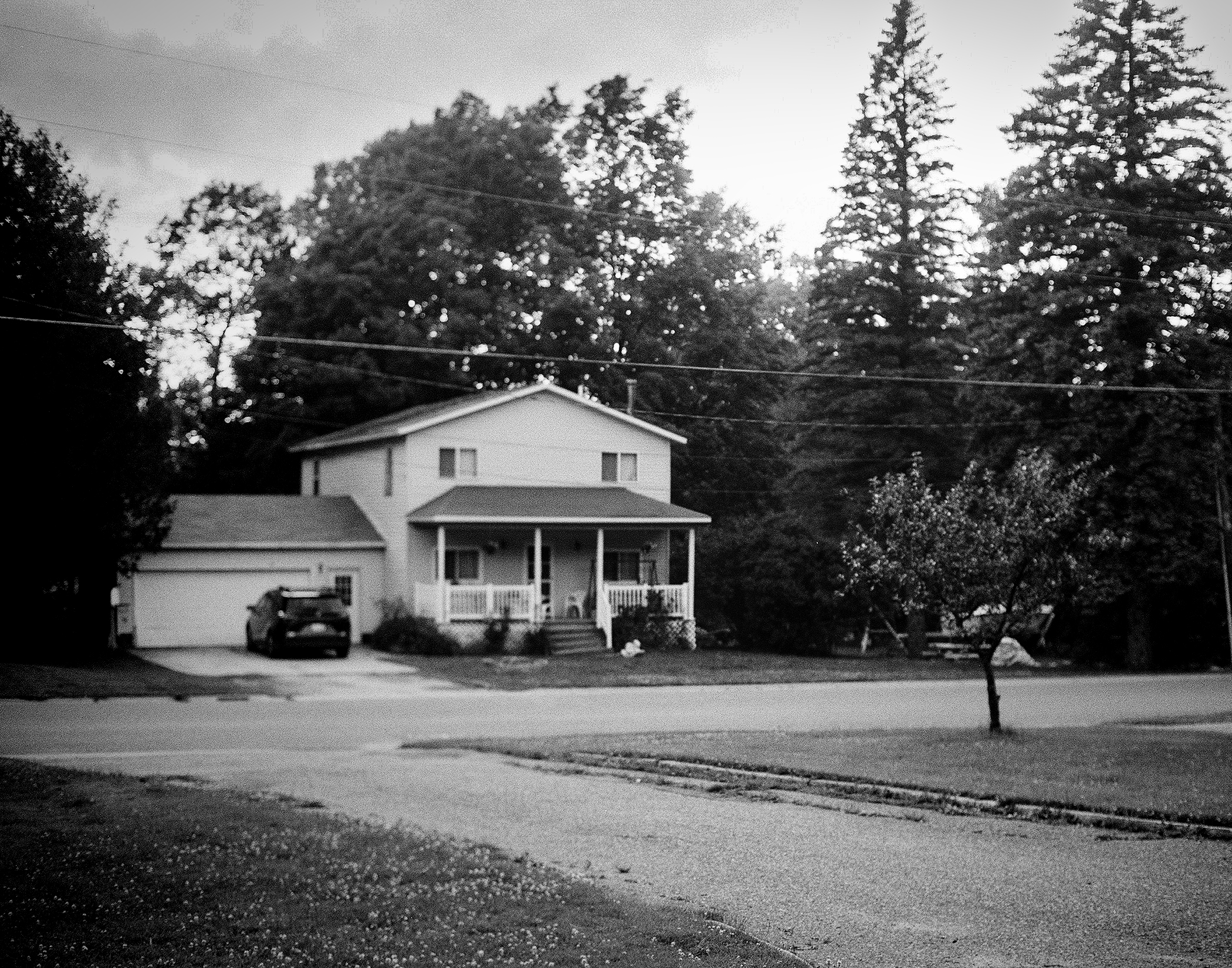 Residential house with attached garage and front porch among tall pine trees