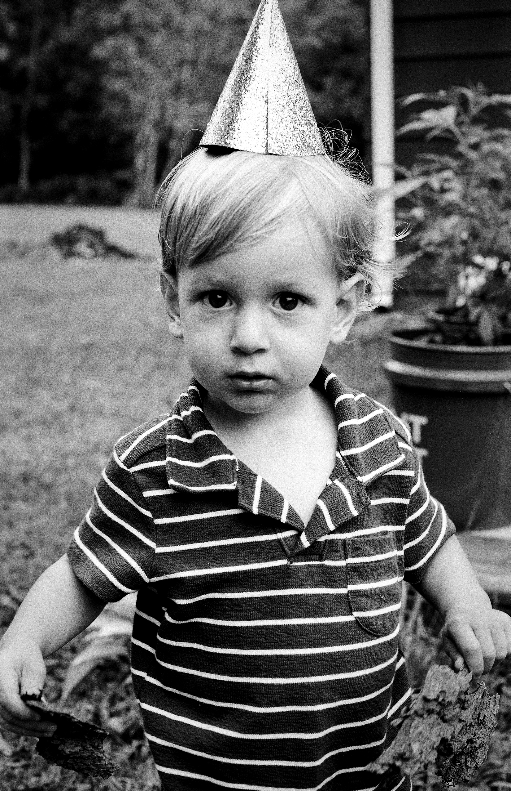 Small child in striped shirt wearing party hat at birthday celebration