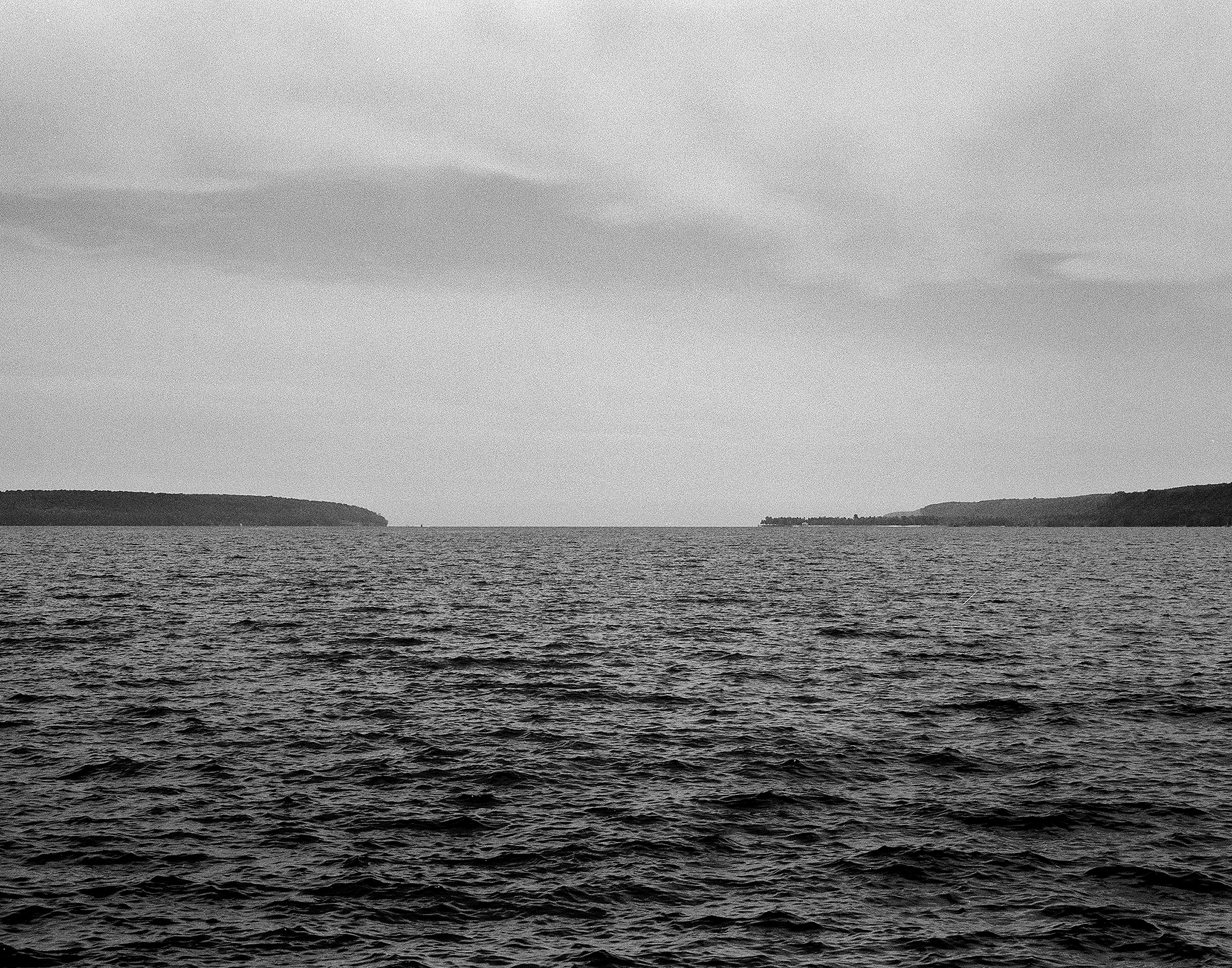 Lake Superior landscape with rocky shoreline and forested bluffs under overcast sky
