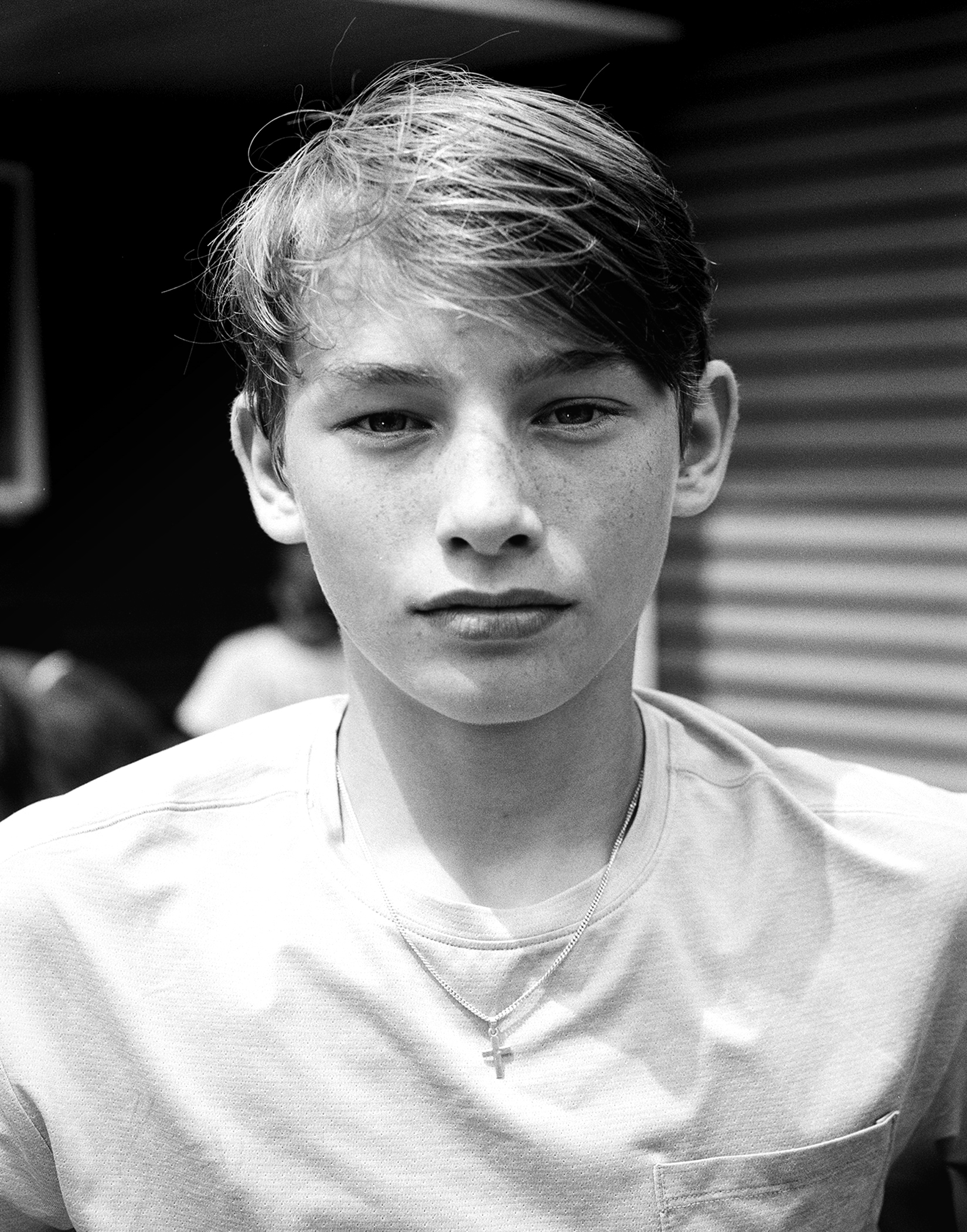 Young man in white v-neck shirt with cross necklace in portrait setting