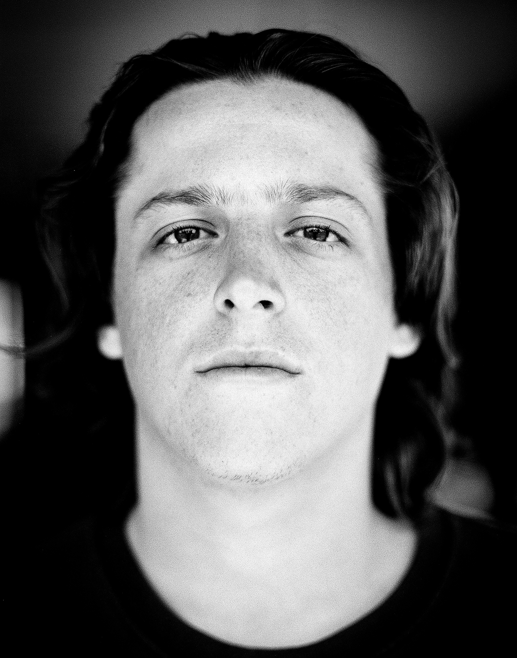 Formal portrait of man with long dark hair in black and white